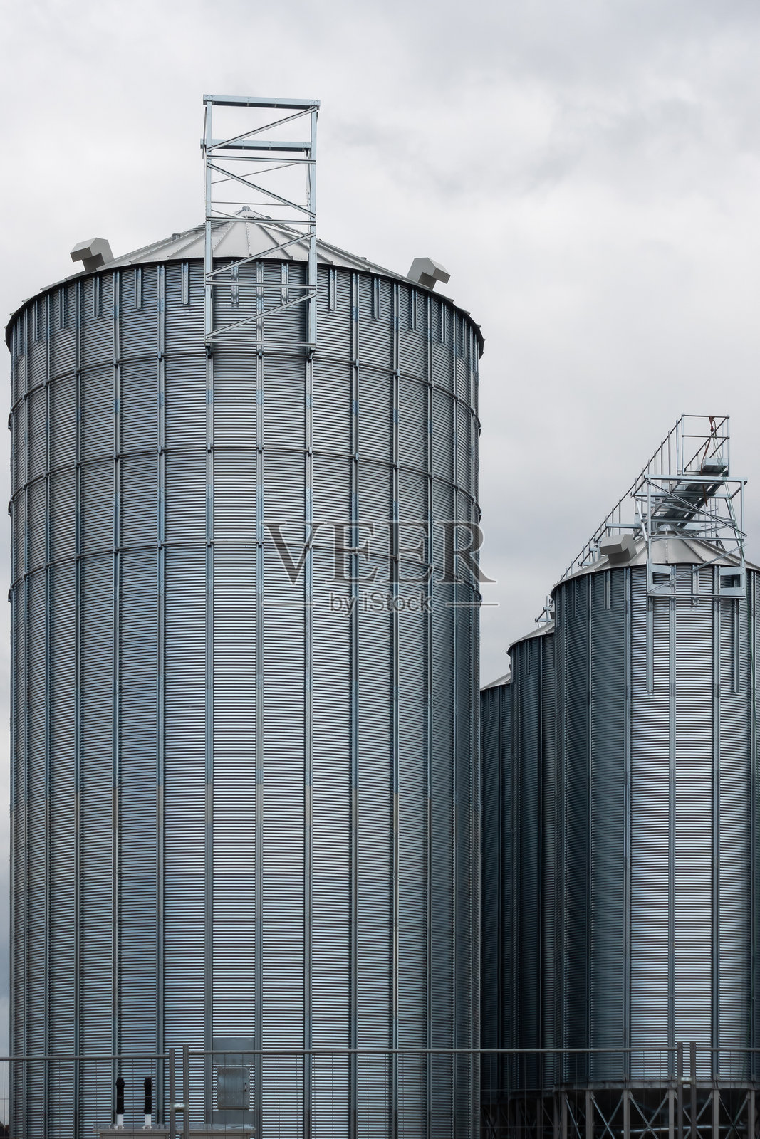 钢铁谷仓映衬着多云的天空。照片摄影图片