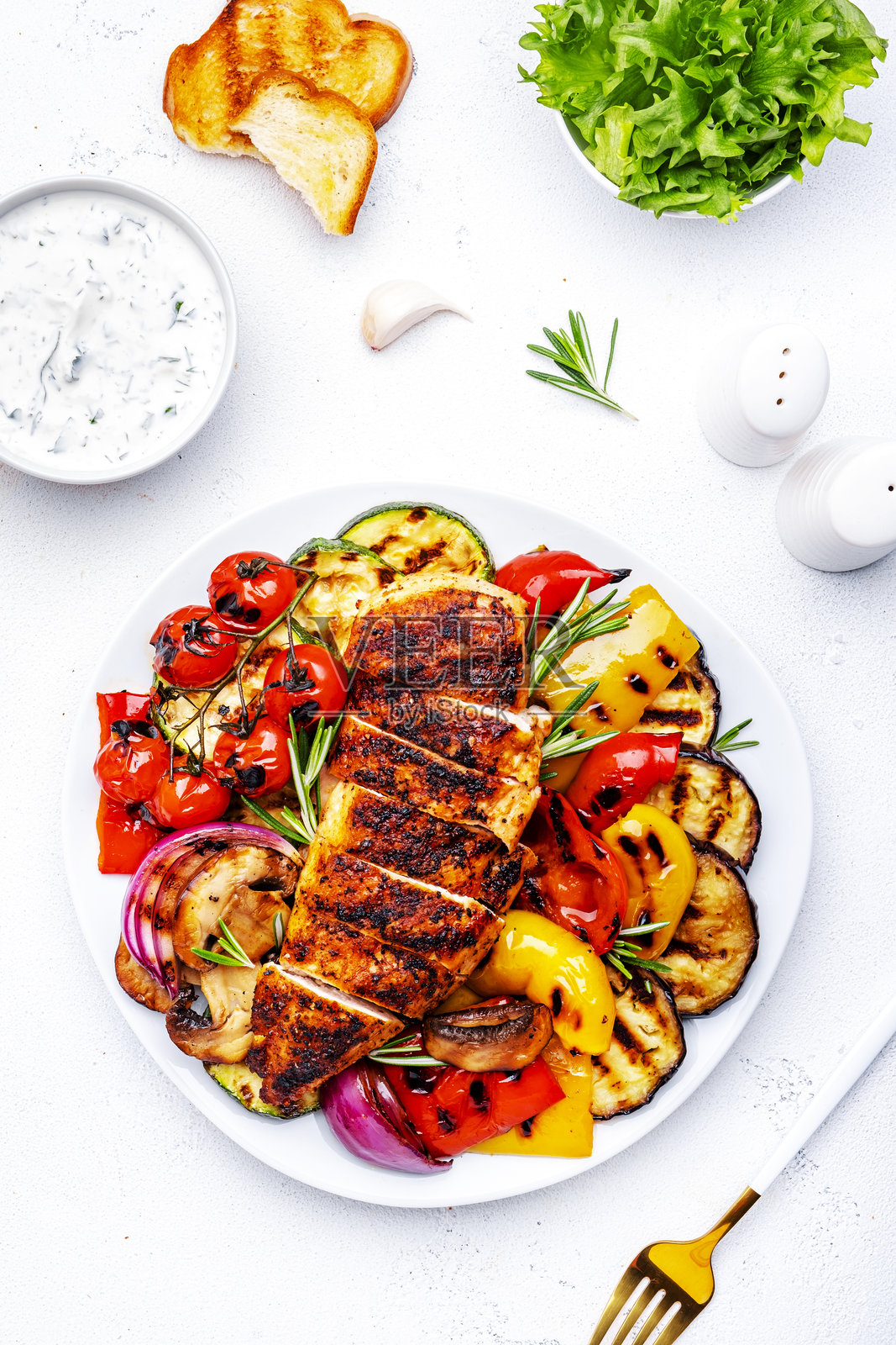 烧烤午餐。烤鸡胸脯和各种蔬菜在盘子里，白色背景，俯视图照片摄影图片