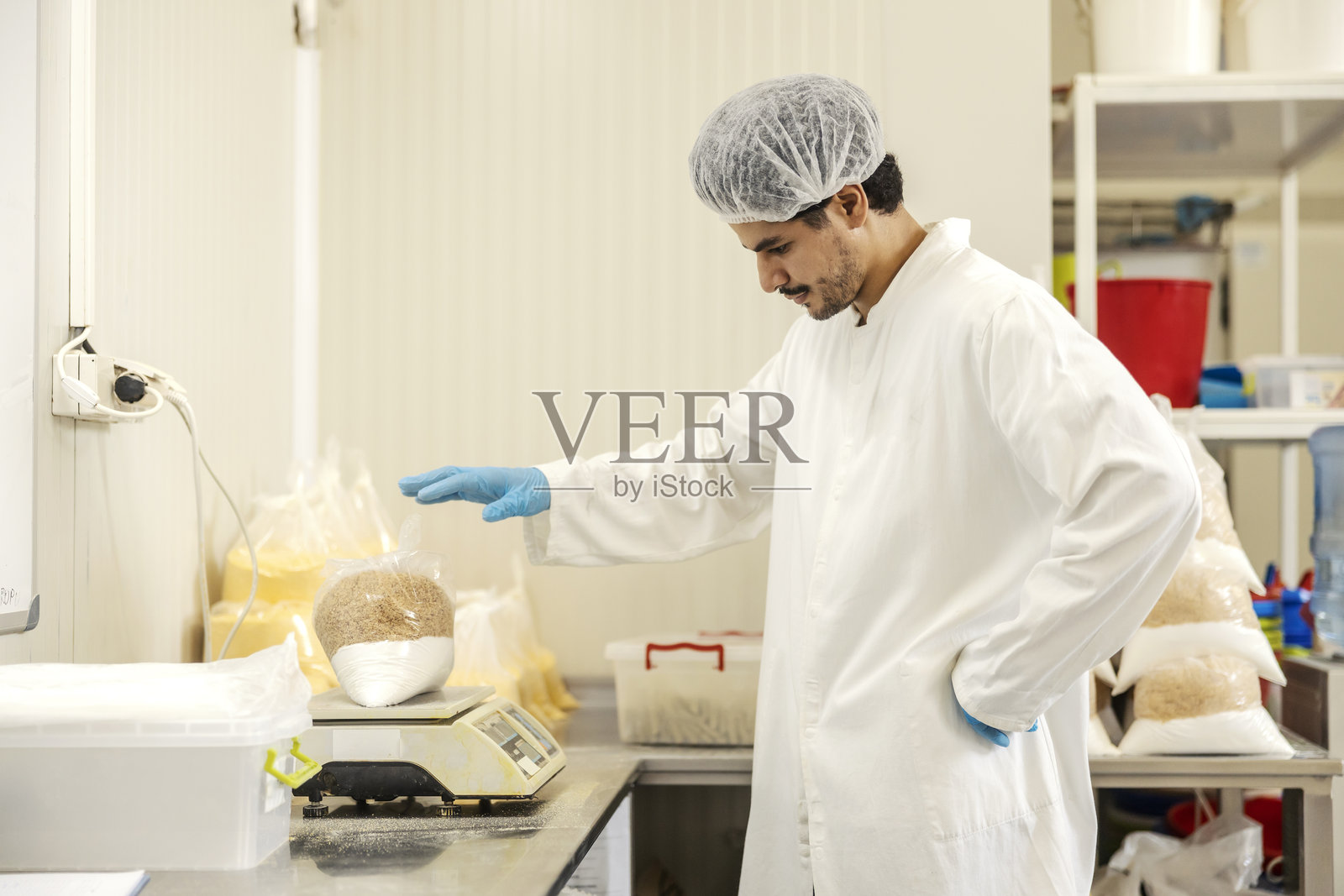 食品厂的面包师用天平测量饼干配料的侧视图。照片摄影图片