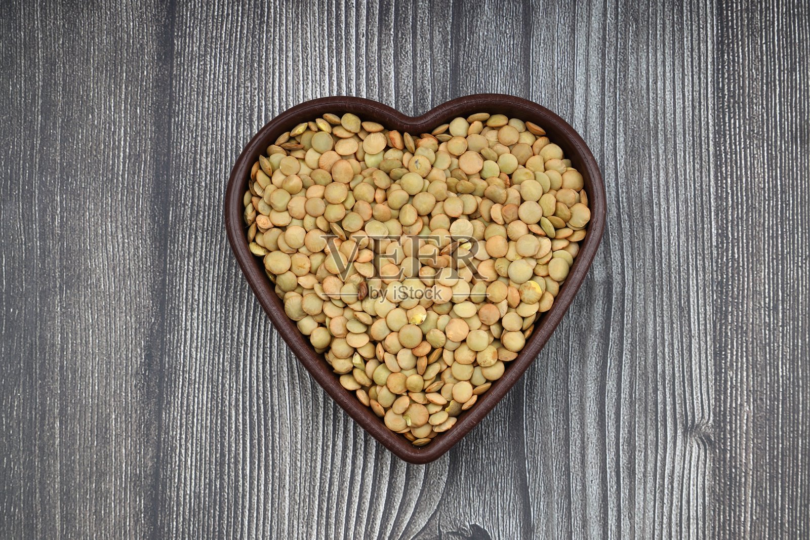 木桌背景上的木碗里装着绿扁豆。俯视图，复制空间。平的。照片摄影图片