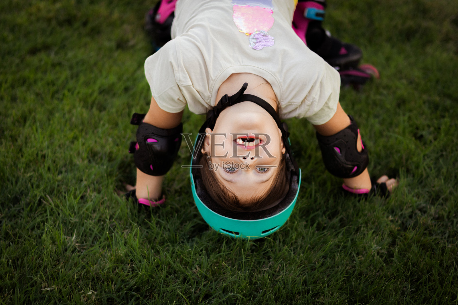在公司大楼附近的公园里，戴着防护装备和头盔，穿着直排轮滑鞋的漂亮好动的女学生照片摄影图片