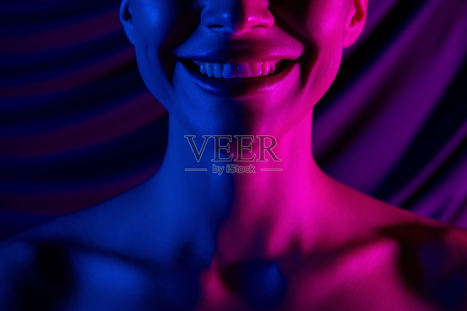 剪裁照片的女孩脖子肩膀微笑白色的牙齿孤立霓虹粉紫色布照片摄影图片