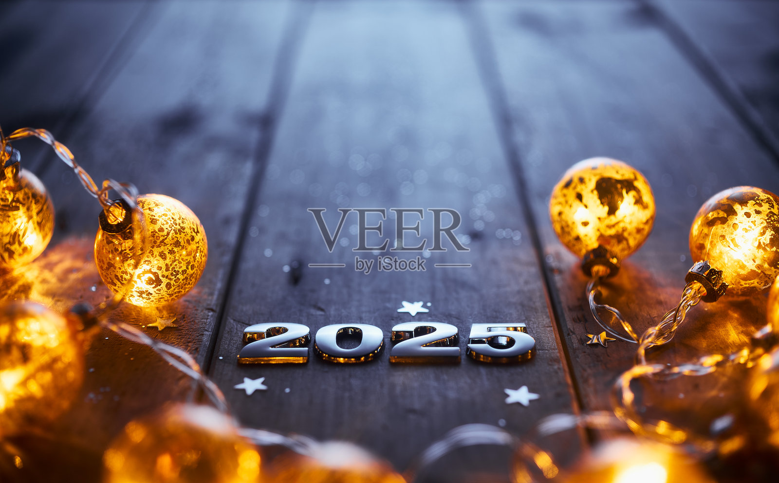2025年新年庆祝场景，金色的发光串灯和质朴的木头上的金属数字照片摄影图片