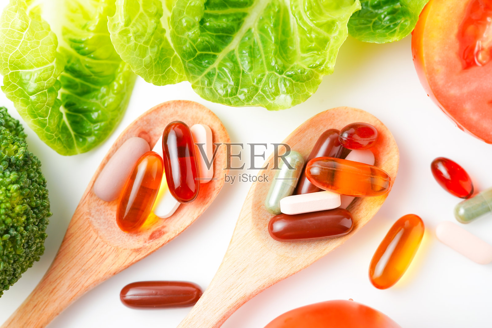 木勺装药丸和胶囊，配新鲜蔬菜，多种维生素和补充剂照片摄影图片