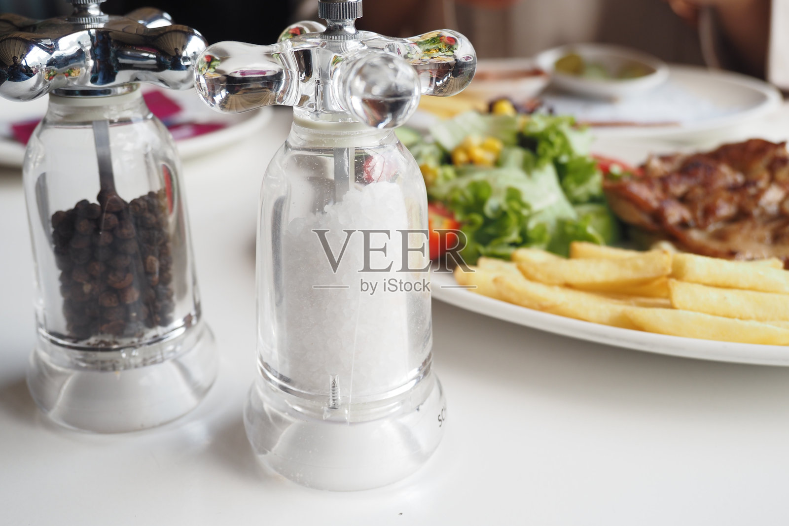 令人愉快的盐和胡椒瓶伴随着美味的饭菜呈现在餐桌上照片摄影图片