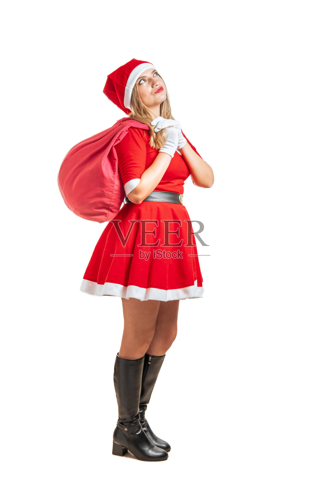 年轻的金发女圣诞老人带着一袋礼物若有所思地走在圣诞节照片摄影图片