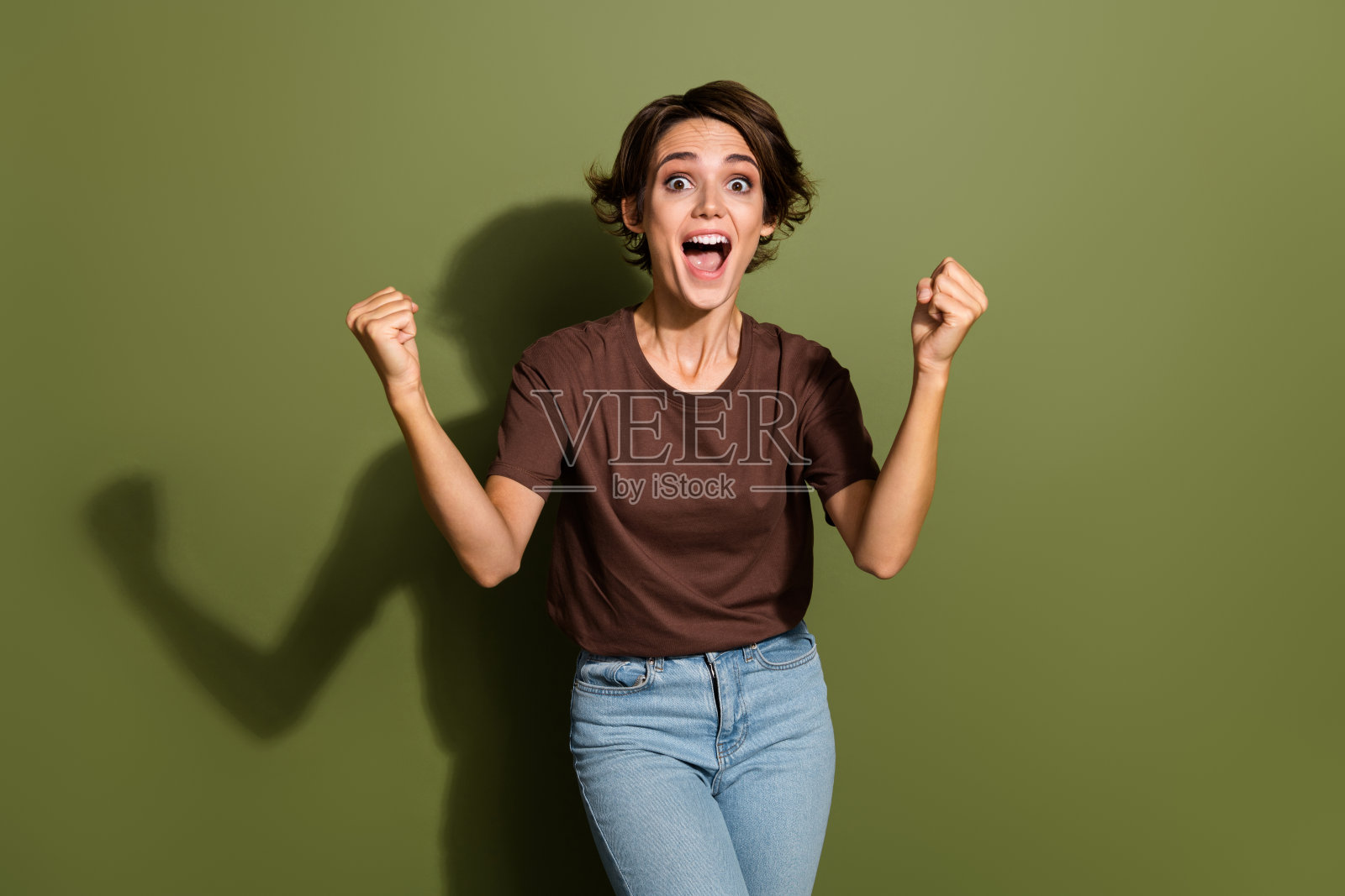 肖像欣喜若狂的疯狂女孩与短发穿着超大的t恤尖叫耶赢投注孤立的绿色背景照片摄影图片