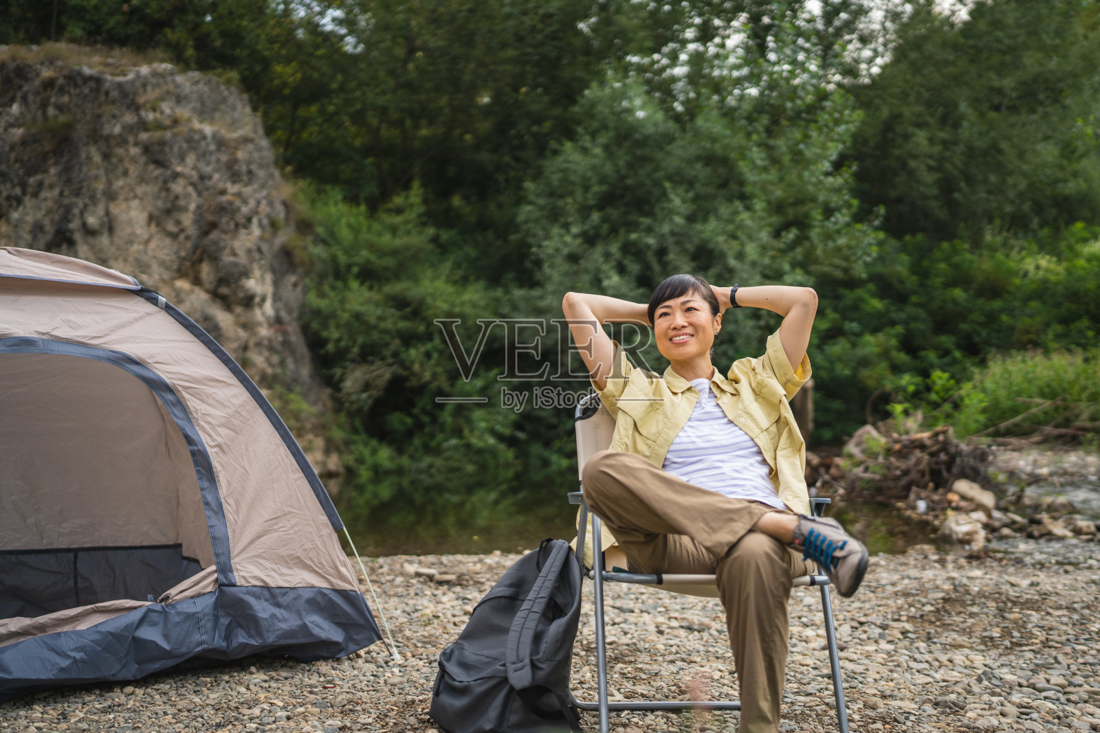 成熟的日本女人坐在帐篷前，伸伸懒腰享受清晨照片摄影图片
