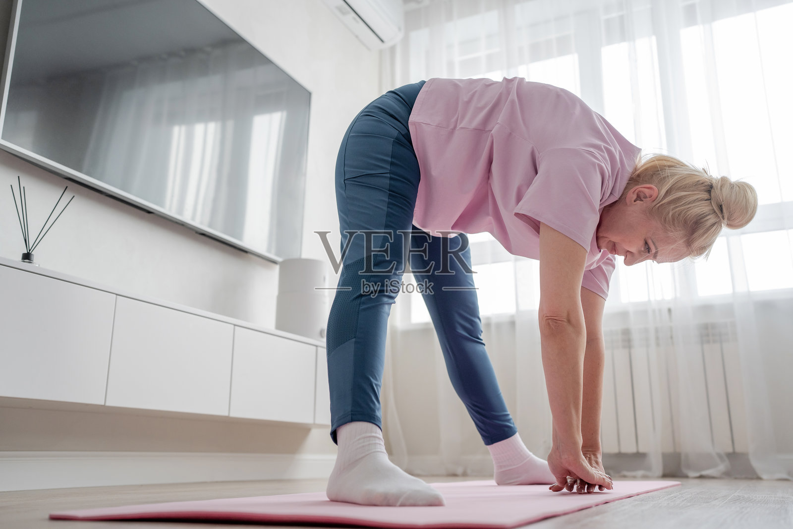 一个女人在舒适的客厅里练习瑜伽，周围是平静的能量和自然光照片摄影图片
