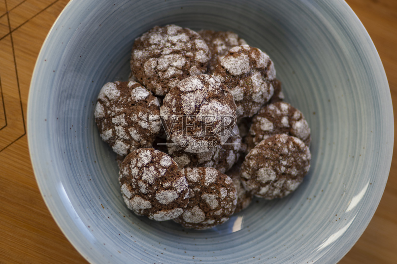 美味的皱纹，棕色和白色巧克力味的可可皱纹饼干覆盖着糖粉在蓝色的碗照片摄影图片