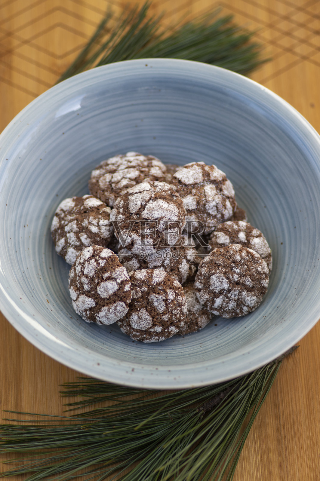 美味的皱纹，棕色的白色巧克力味的可可皱纹饼干覆盖着糖粉在蓝碗松枝照片摄影图片