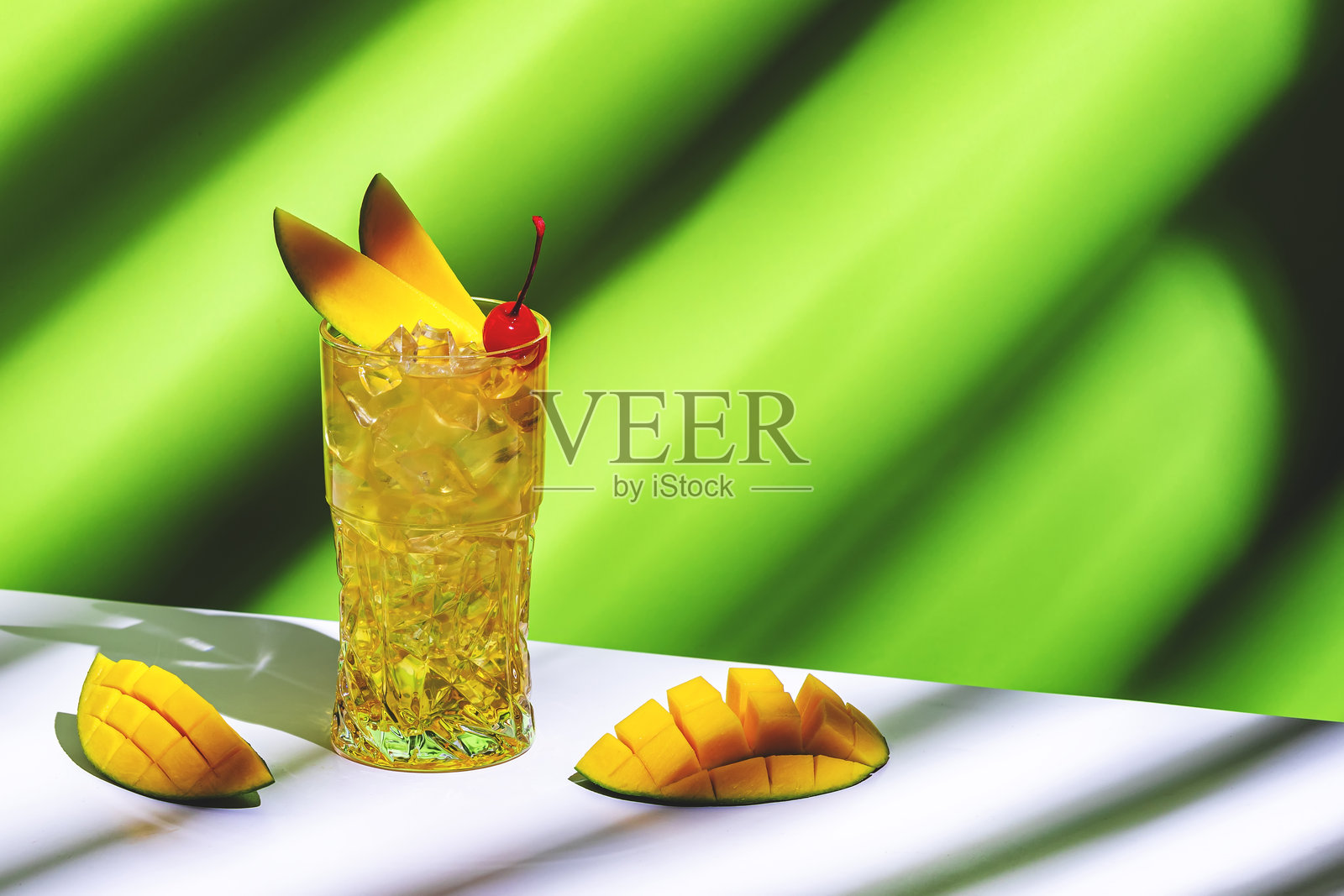 芒果和朗姆酒酒精鸡尾酒饮料，糖浆，姜汁啤酒，柠檬汁和冰块。绿色背景，硬光照片摄影图片