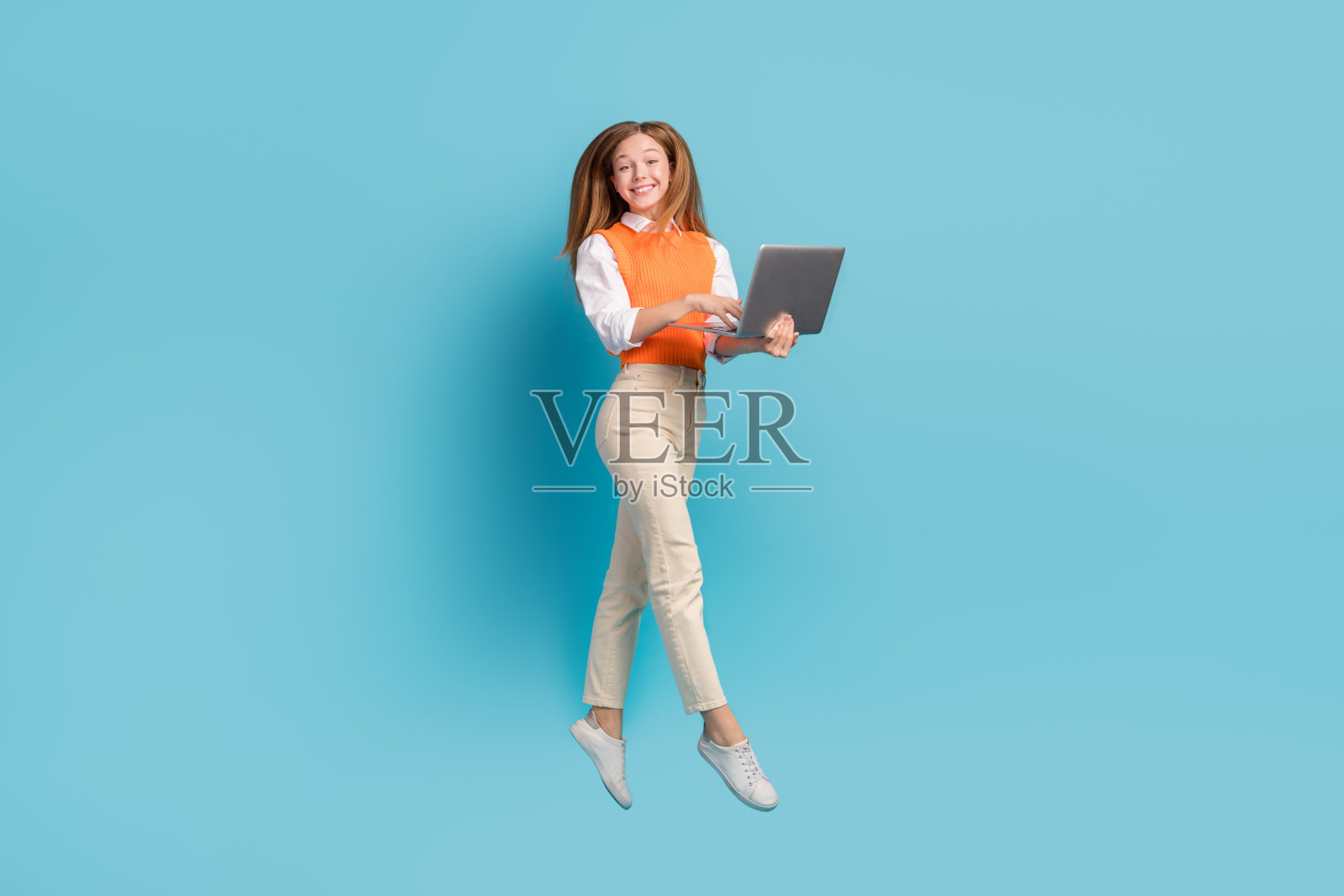 可爱的小积极的女士的全身照片飞空气使用现代设备小工具广告上网本孤立的蓝色背景照片摄影图片