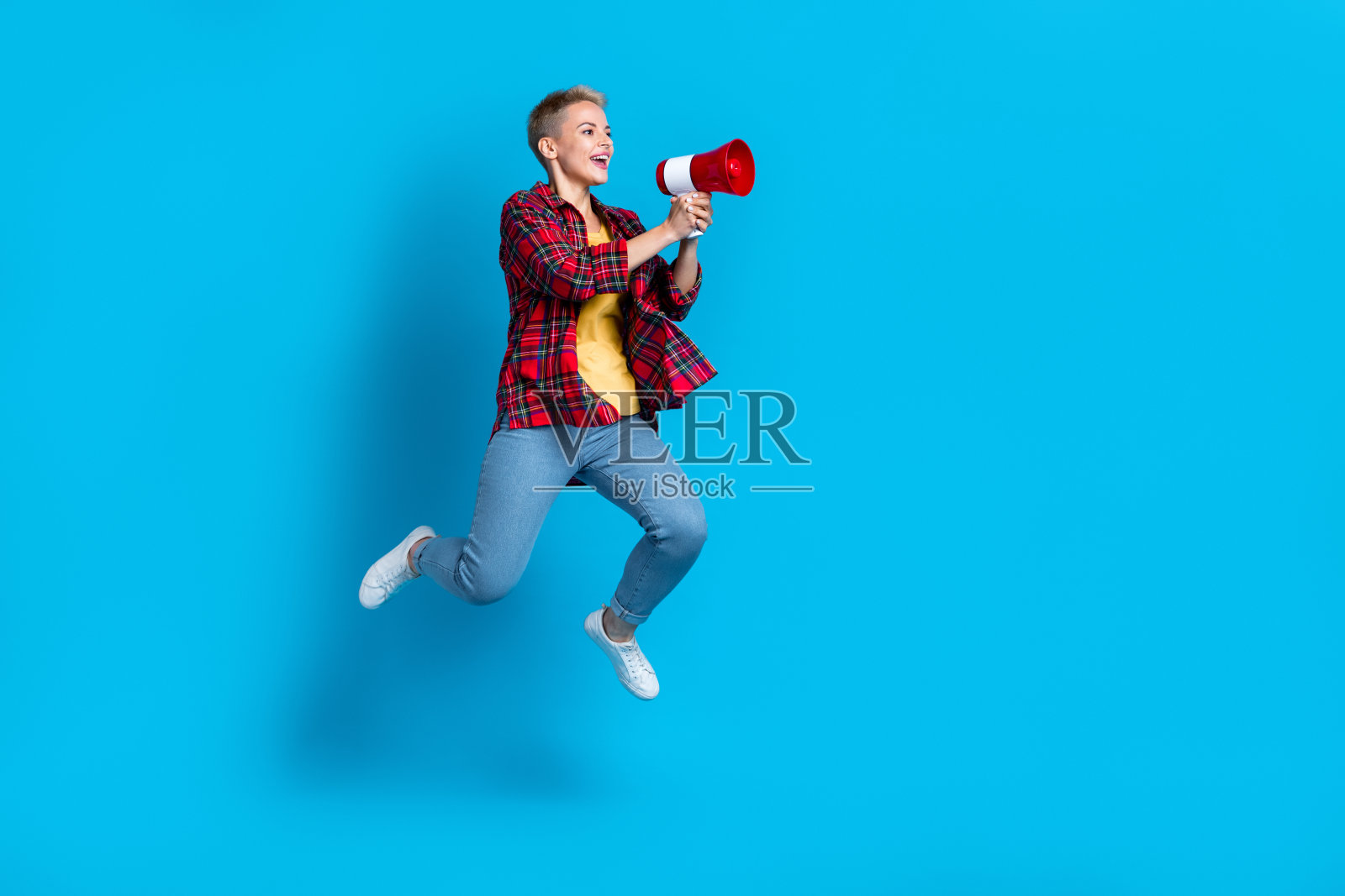年轻时髦的女学生活动家的全长照片空旷的空间，响亮的声音，扩音器尖叫公告孤立的蓝色背景照片摄影图片