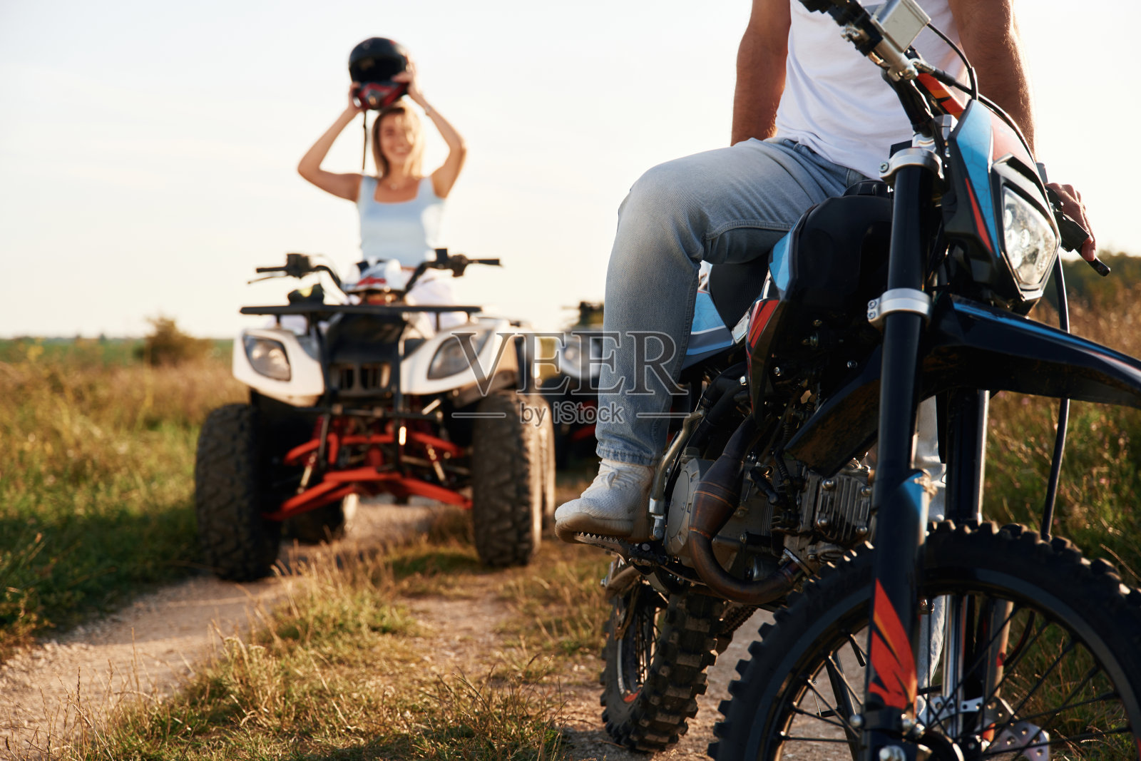 男人骑摩托车，女人骑沙滩车，一起在户外照片摄影图片
