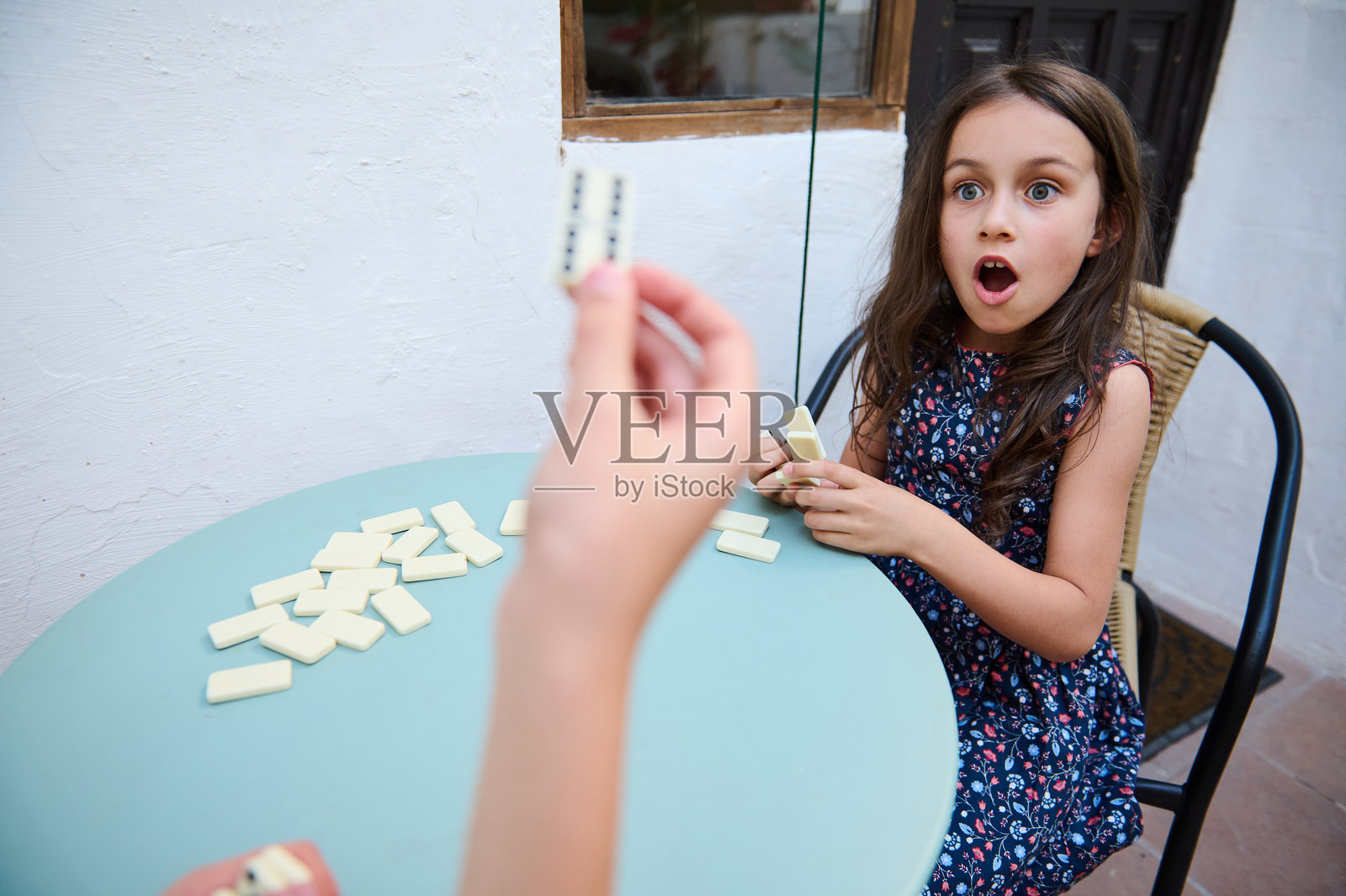 惊讶的年轻女孩在户外玩多米诺骨牌，在一个有趣的环境中表现出兴奋和情感，专注于策略和乐趣。照片摄影图片