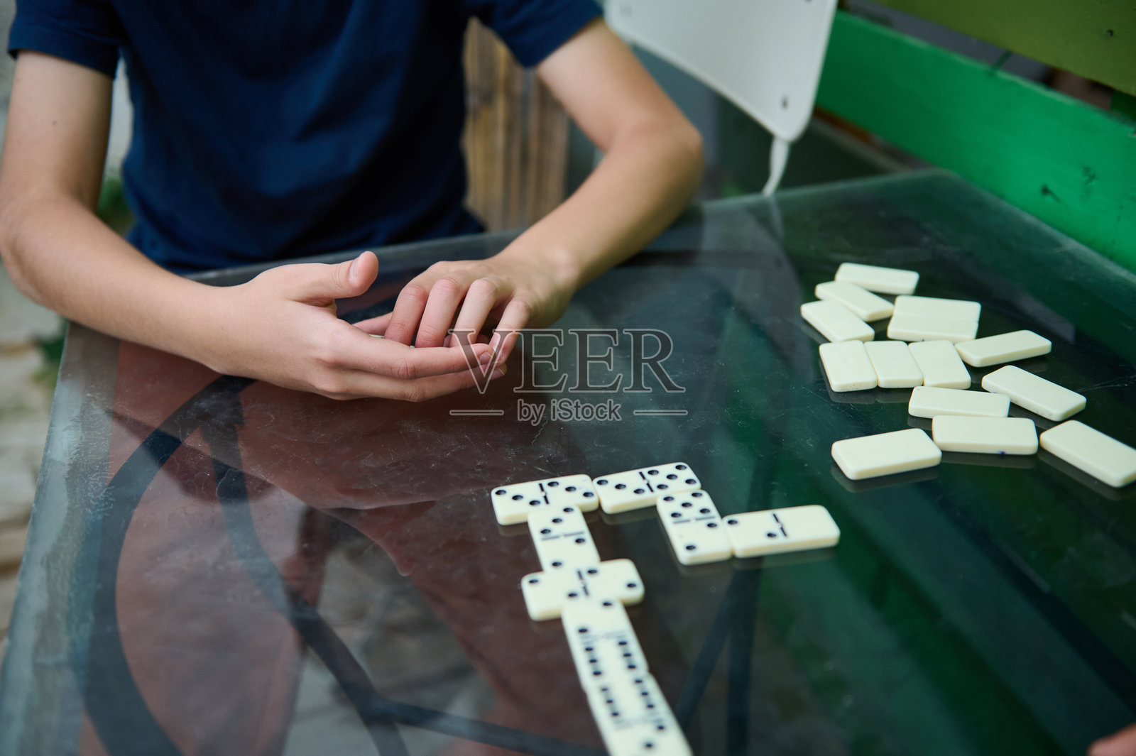 孩子在玻璃桌上玩多米诺骨牌，在宁静的户外环境中思考下一步的行动照片摄影图片
