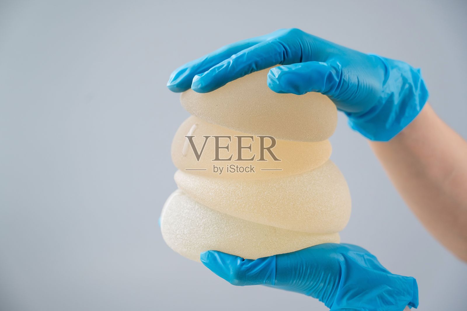 整形外科医生拿着乳房硅胶植入物。照片摄影图片