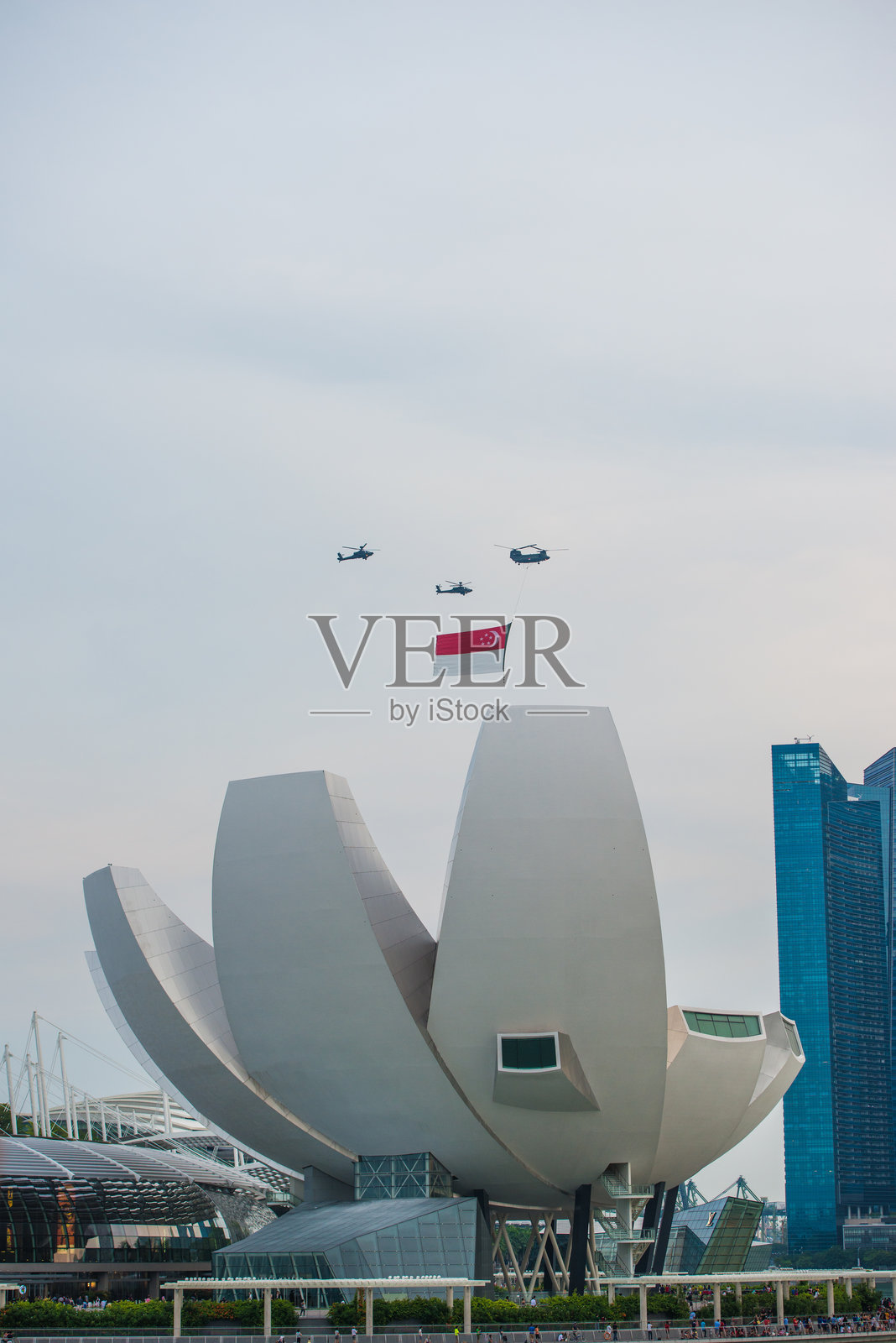 悬挂着新加坡国旗的直升机在城市上空飞行照片摄影图片