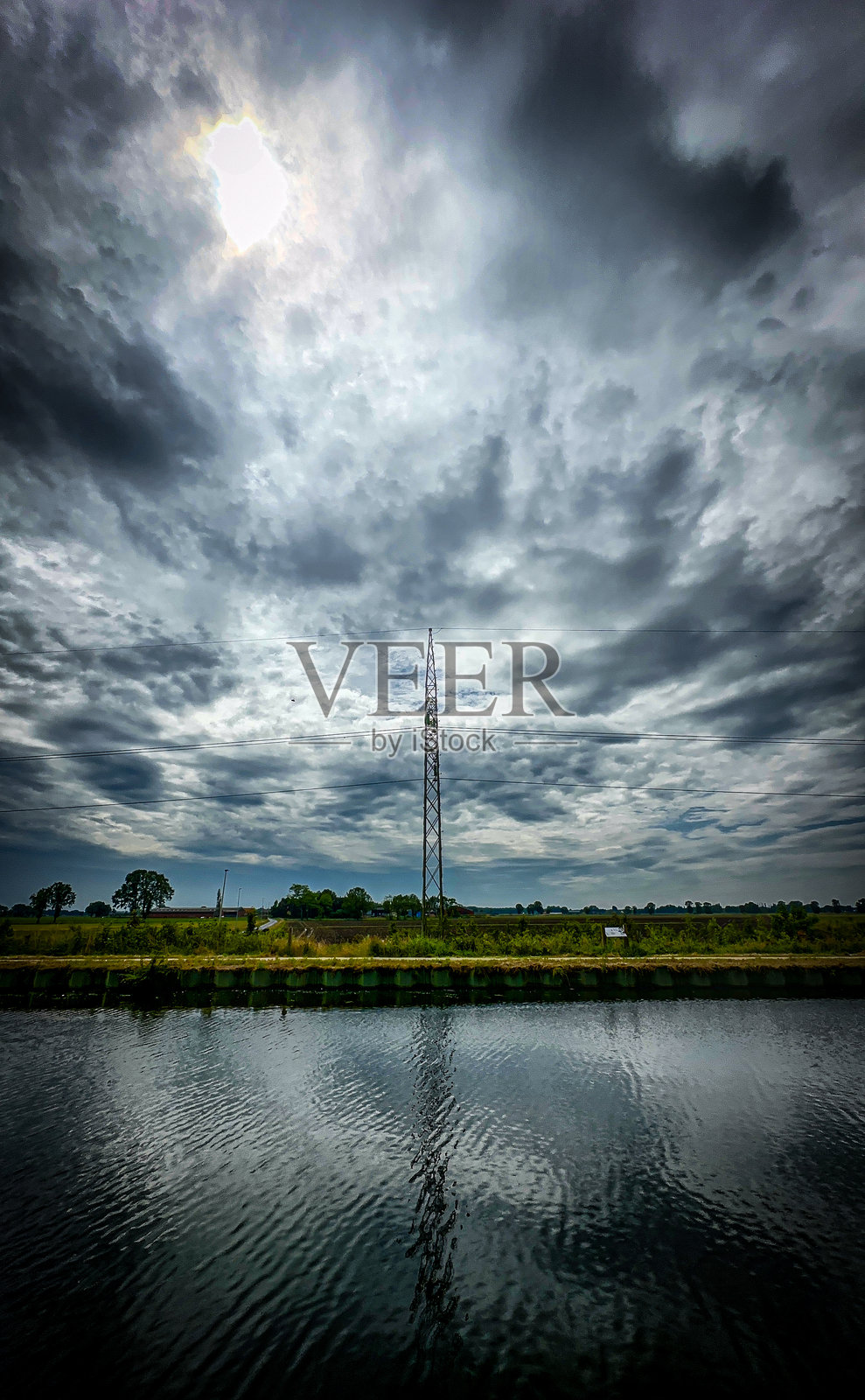 塔美丽地映在宁静的水面上，上面是戏剧性的云照片摄影图片