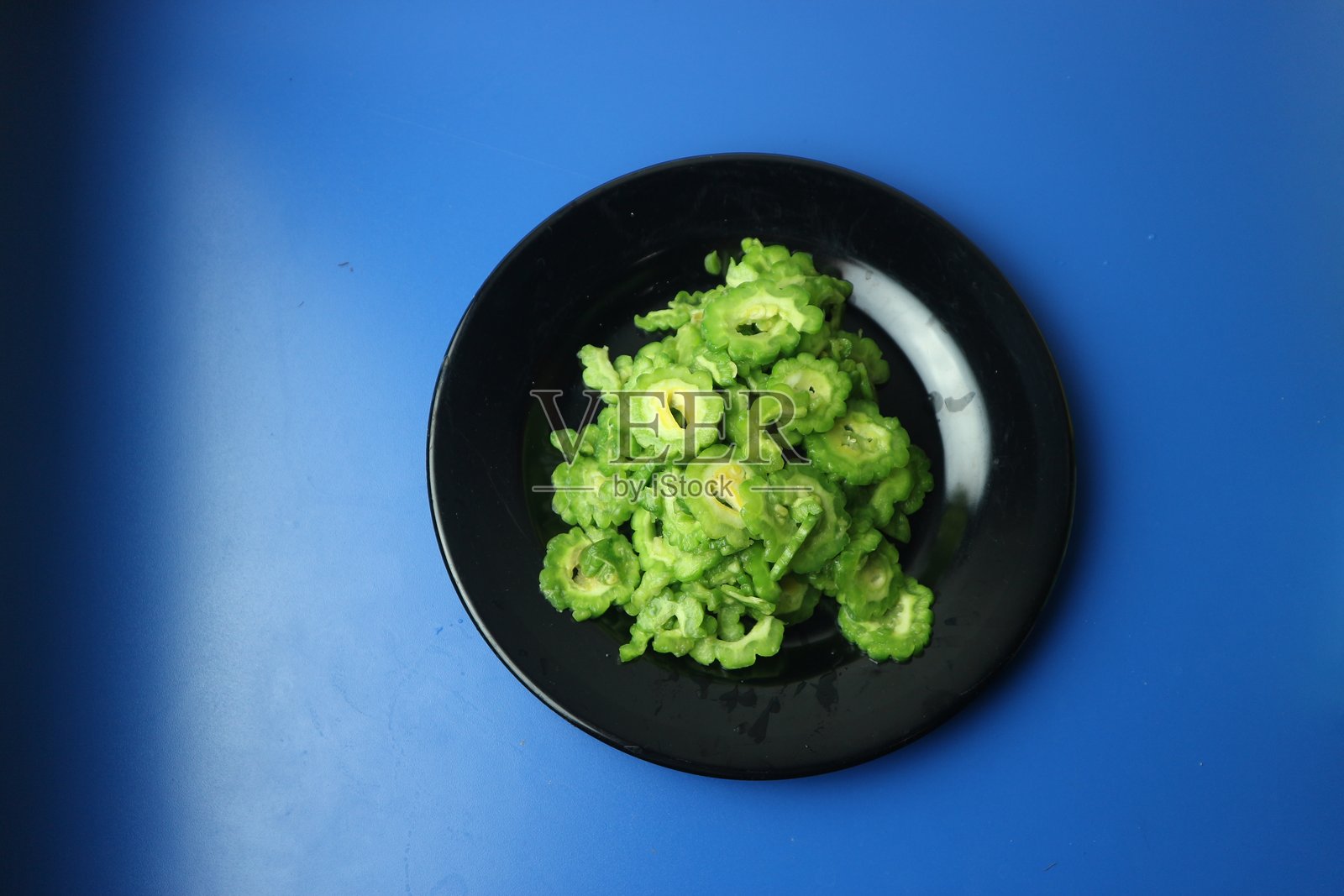 一种叫做苦瓜或苦瓜的食用蔬菜，装在黑色盘子里照片摄影图片