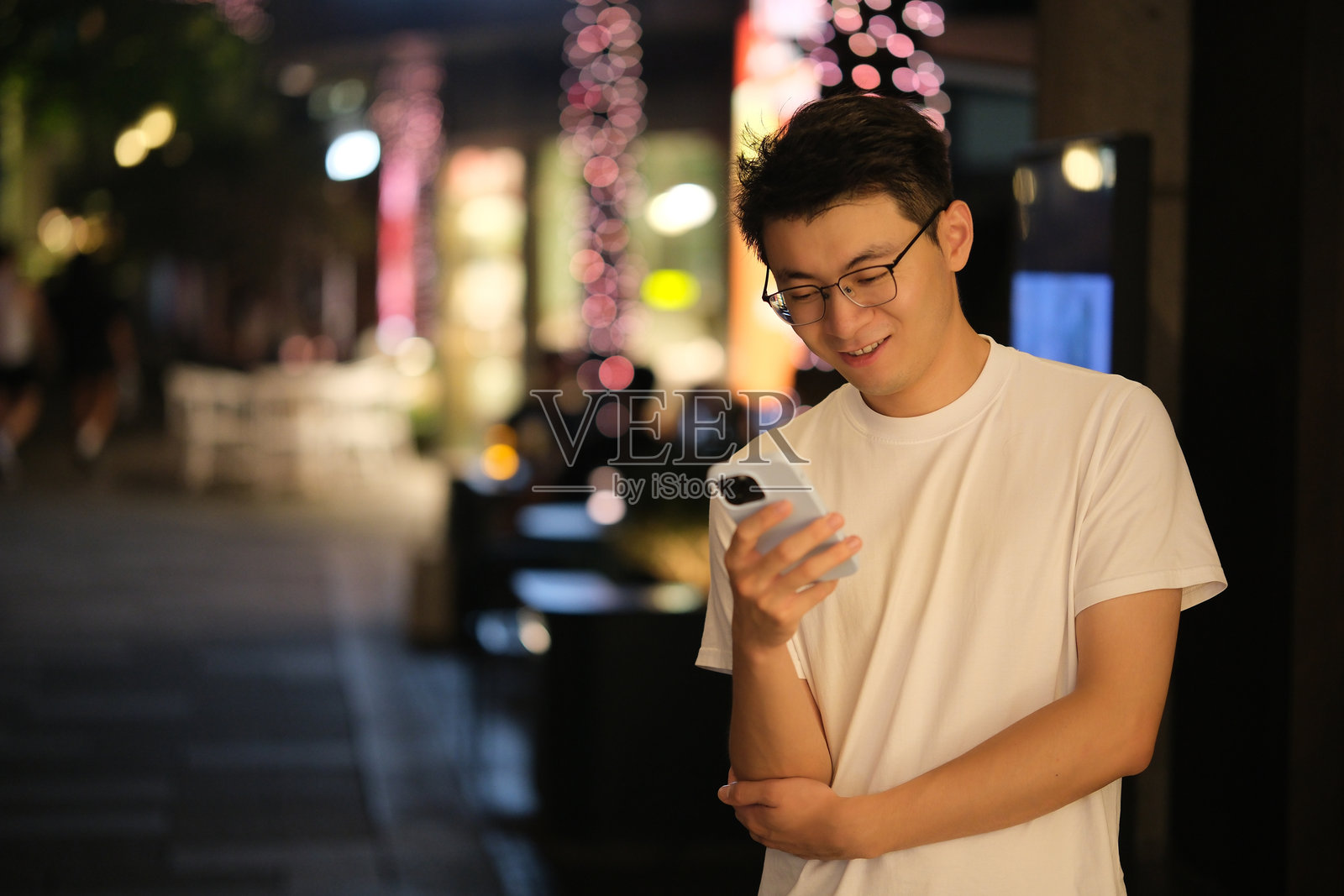 亚洲年轻人晚上看手机照片摄影图片