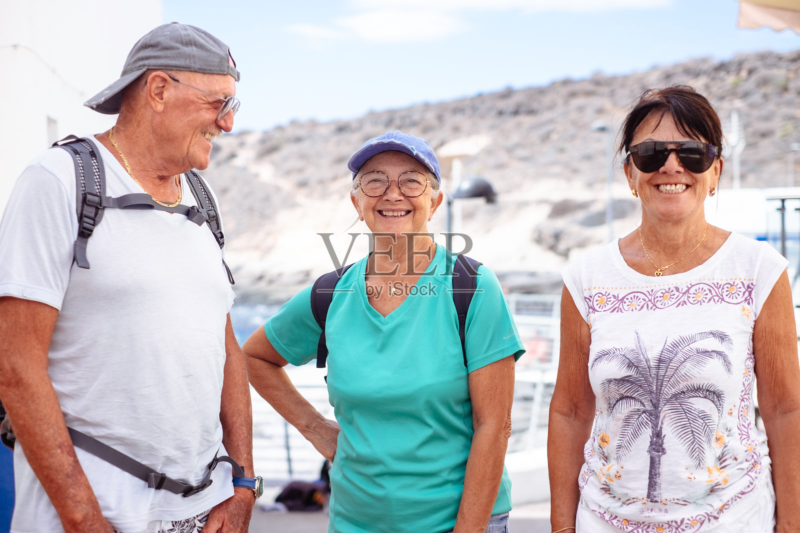 在海边背着背包的快乐的白人高年级朋友。老年人步行参观特内里费岛，享受健康的生活方式和阳光明媚的一天照片摄影图片