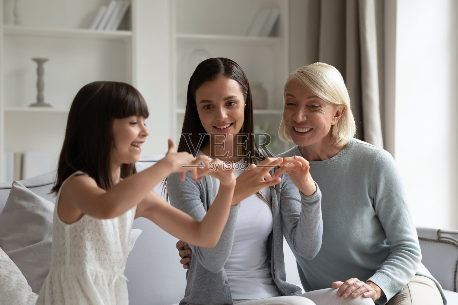 微笑的小女孩与母亲和祖母练习手语照片摄影图片