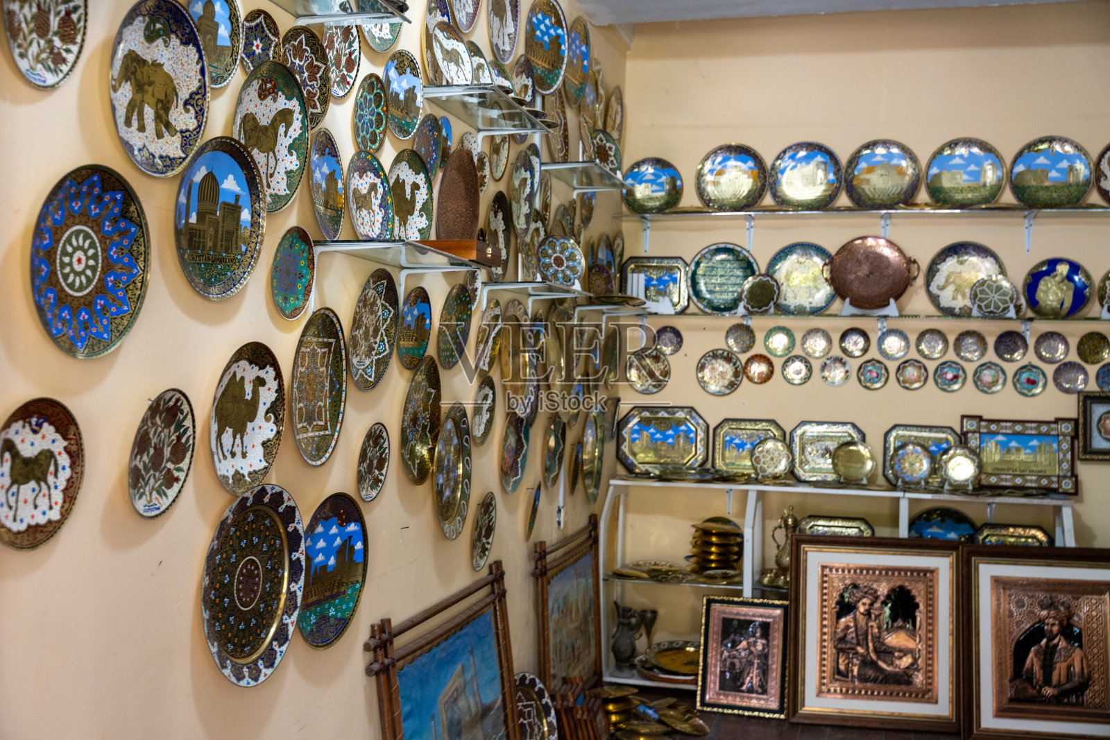 满墙的盘子和碗以蓝天为背景。盘子大小不同，图案各异，墙上装饰着各种画框照片摄影图片