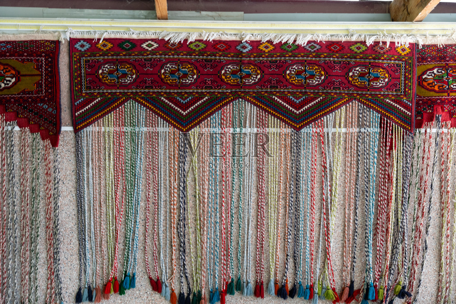 墙上挂着一条镶着珠子的彩色地毯。地毯是用不同颜色的线做成的，有独特的设计照片摄影图片