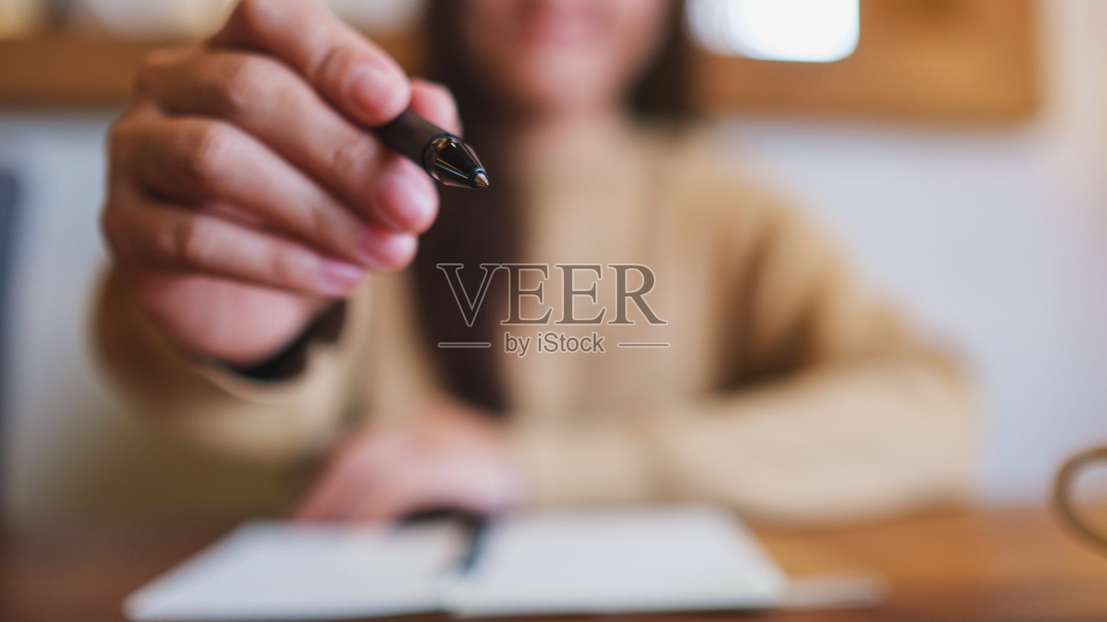 一个女人握着一支笔并伸出手的特写图片照片摄影图片