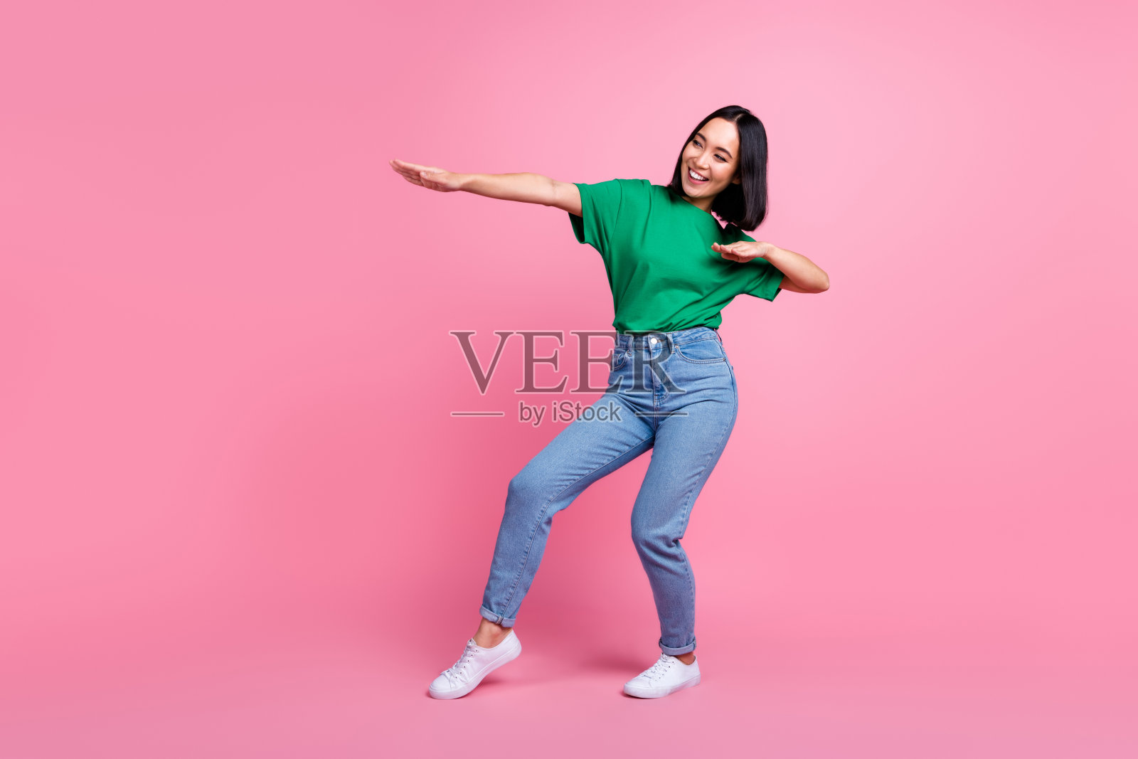 在粉红色的背景上，开朗悠闲的女士全身肖像有乐趣地跳舞，令人心寒照片摄影图片