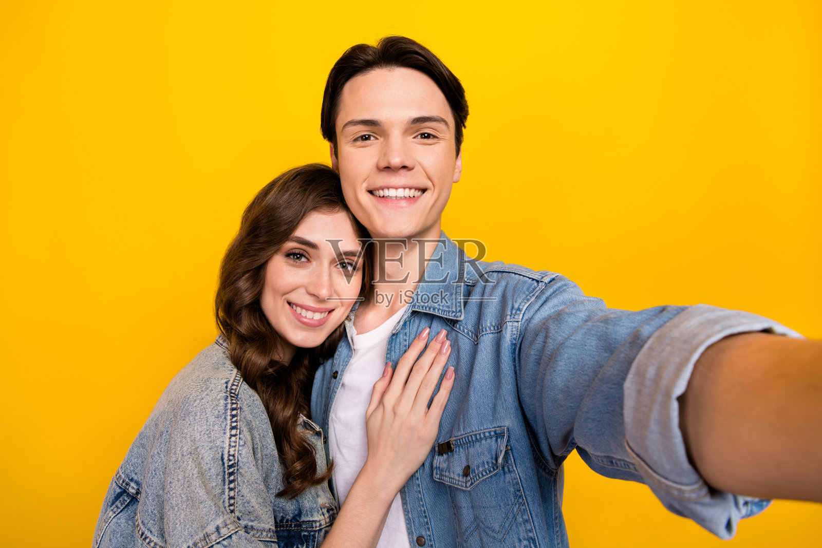 黄色背景下，两个安静可爱的人依偎在一起自拍，笑容灿烂照片摄影图片