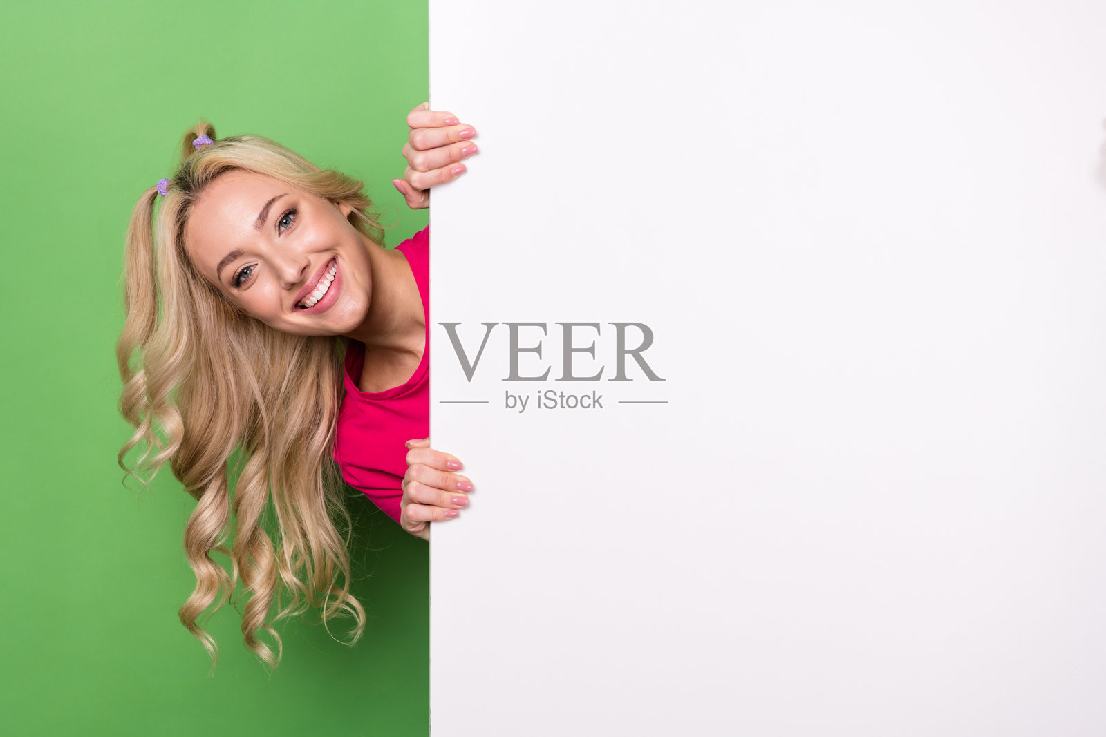 照片的华丽时髦的女士露齿微笑窥视背后的空白空间标语牌孤立的绿色背景照片摄影图片