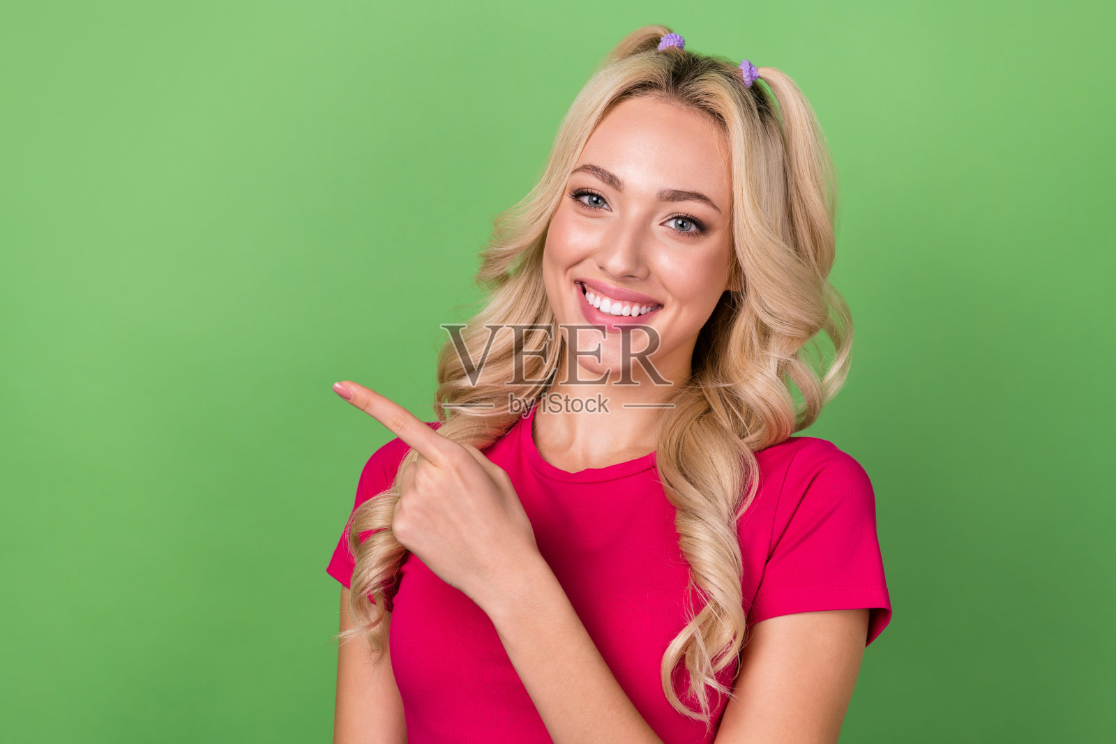 照片中，令人惊叹的积极女孩微笑着，手指空白的空间被隔离在绿色背景上照片摄影图片