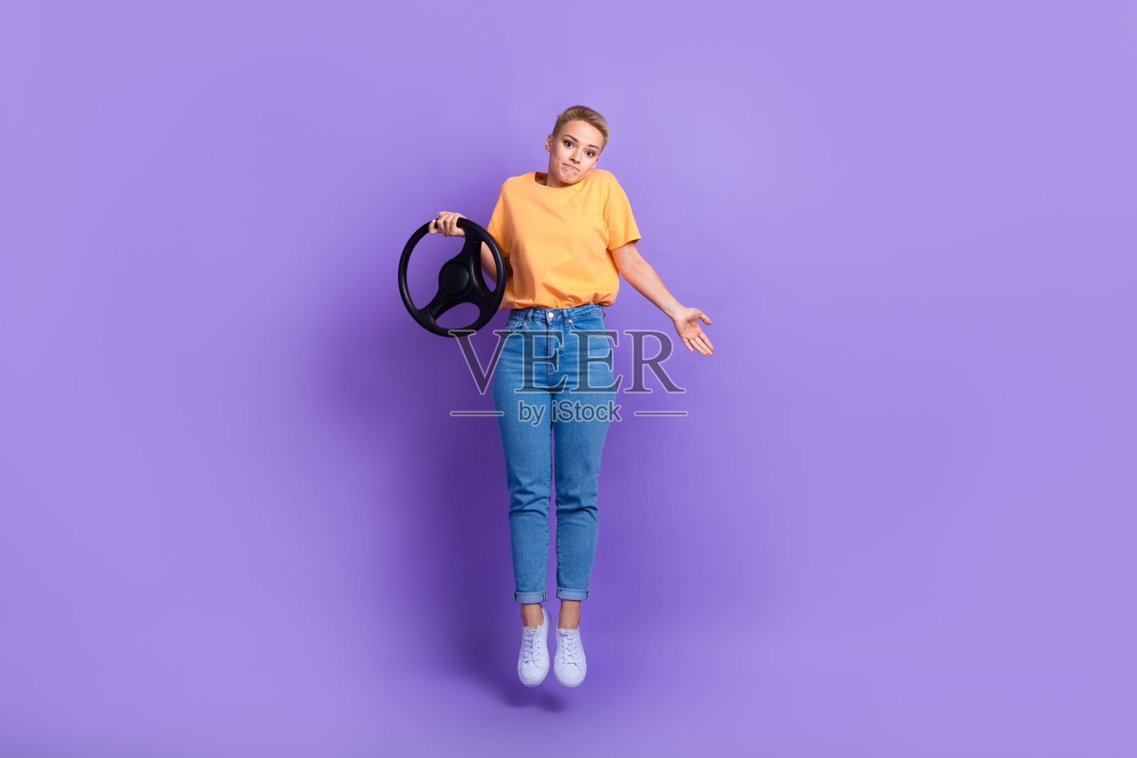 全身照片困惑犹豫的女孩穿着白色运动鞋牛仔裤裤子拿着方向盘孤立的紫罗兰色背景照片摄影图片