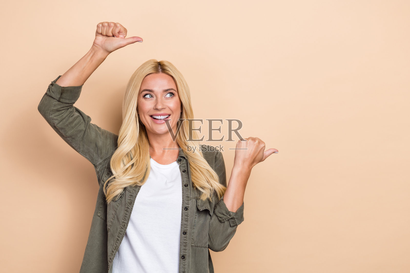 照片中华丽快乐的女士穿着时尚的牛仔服装，两臂直接空白的空间横幅新闻孤立在米色背景上照片摄影图片