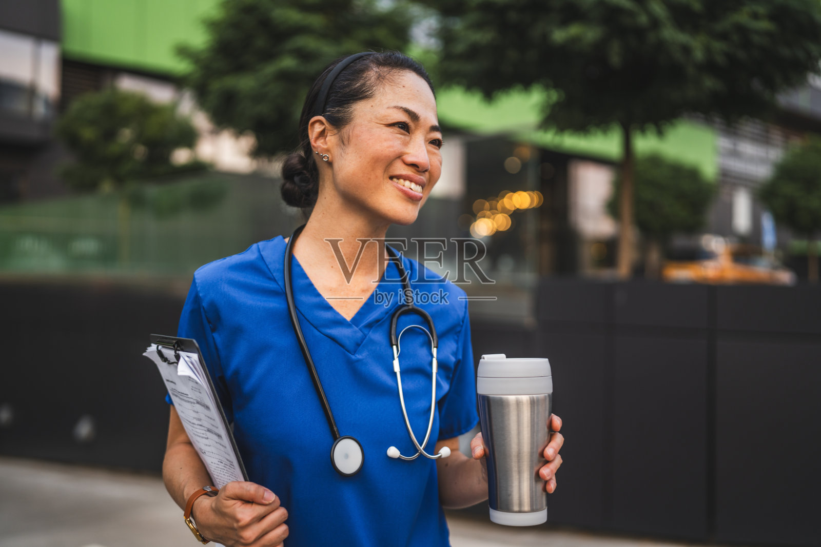 日本医生的肖像站着，拿着写字板和保温瓶照片摄影图片