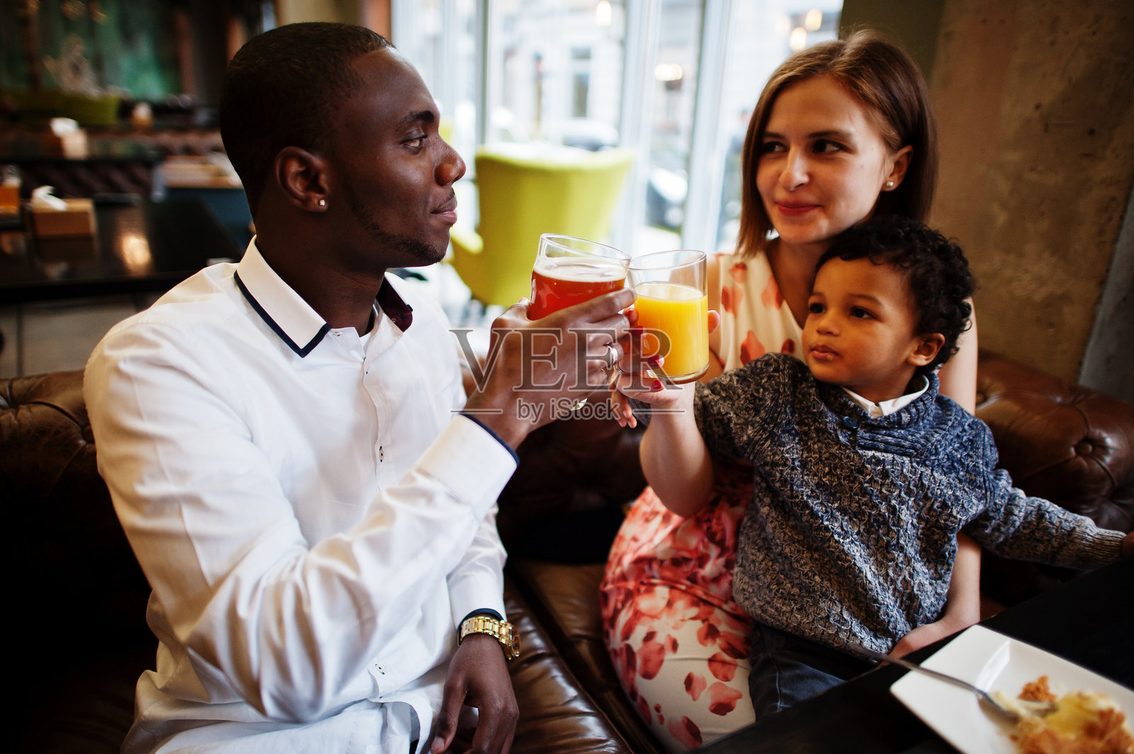 快乐的多民族家庭和男孩一起在餐厅度过时光。非洲男人和欧洲白人女人的关系。照片摄影图片