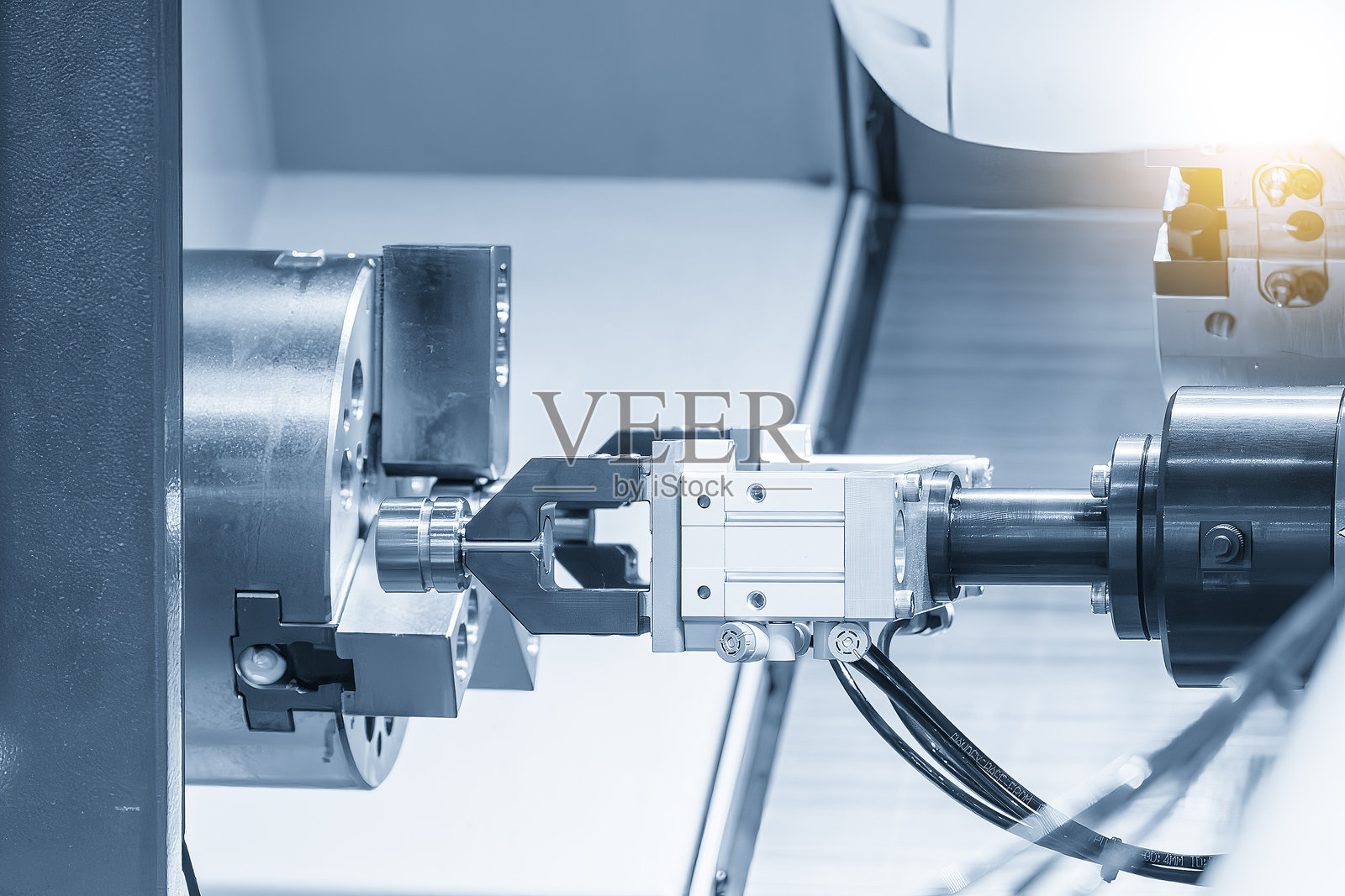 自动机械臂从数控车床上抓取金属零件。照片摄影图片