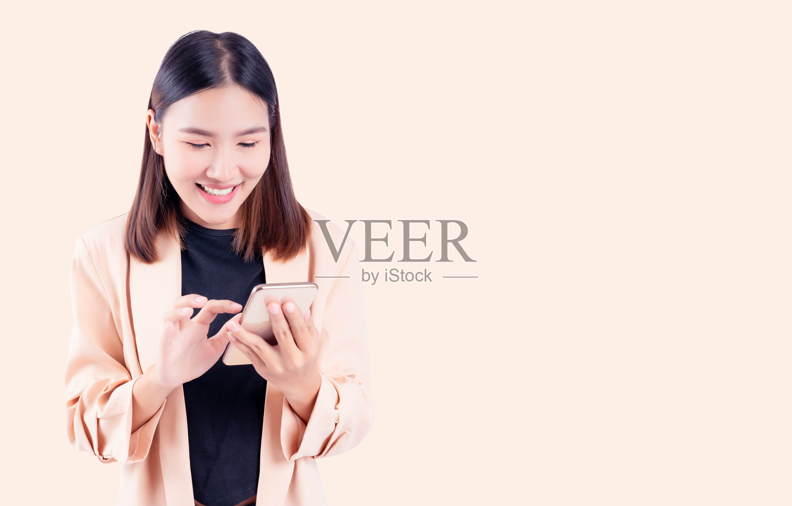 微笑快乐的年轻亚洲女商人用手机站在孤立的淡米色背景和副本照片摄影图片