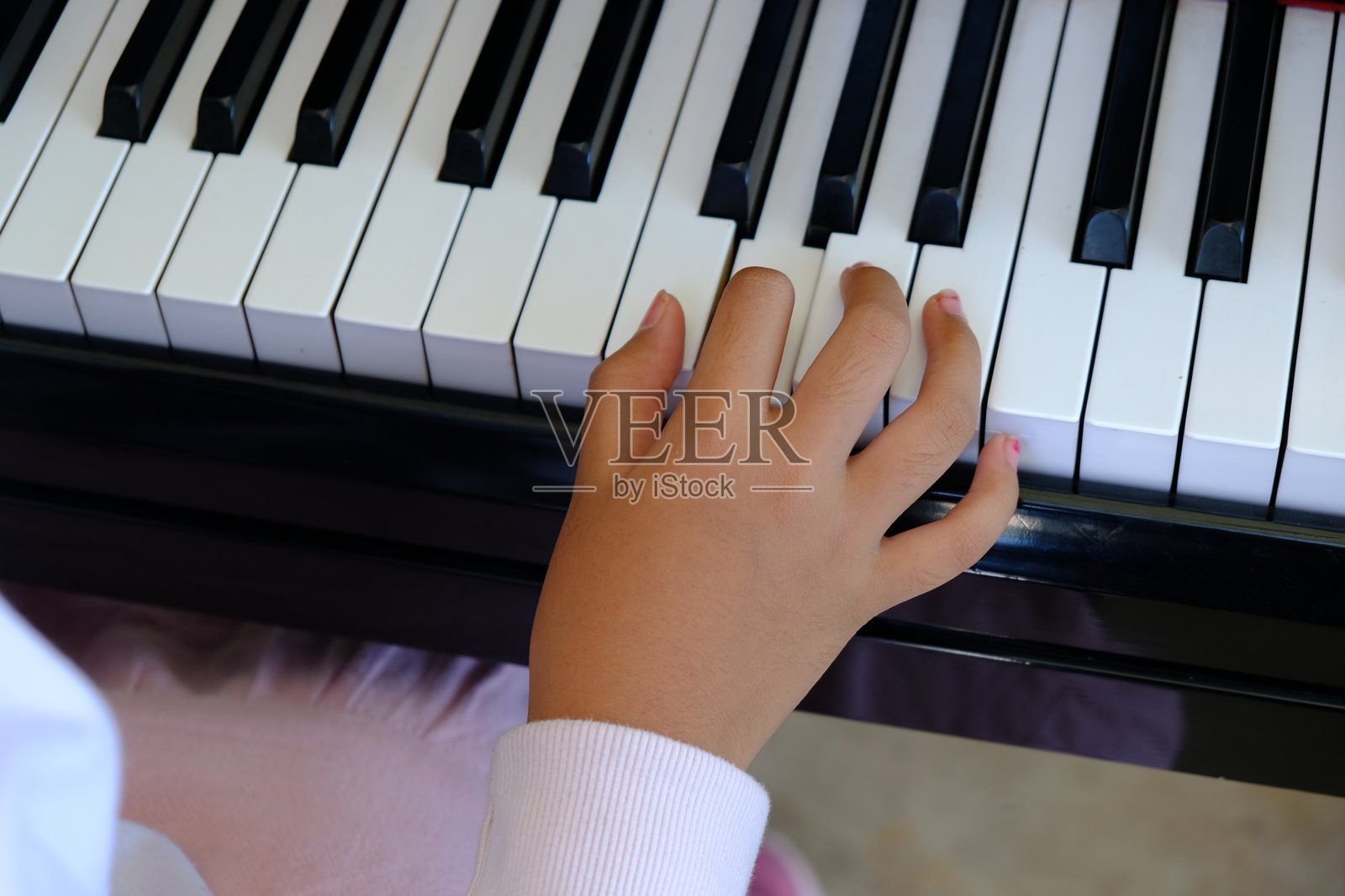 一个女孩的手在按钢琴键，演奏着音乐。照片摄影图片