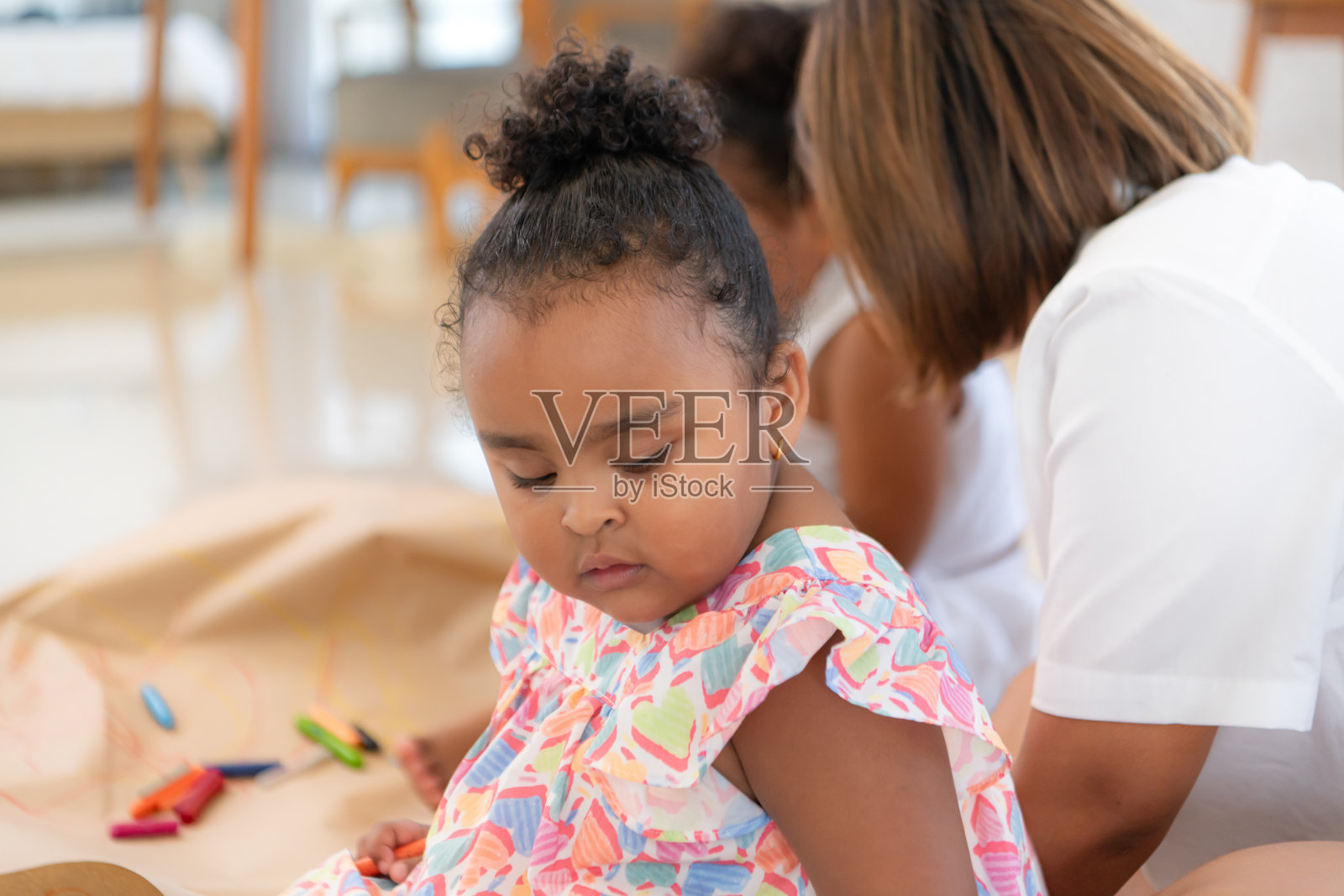 假日里，一位妇女和她的两个小女儿坐在客厅的地板上一起画画照片摄影图片