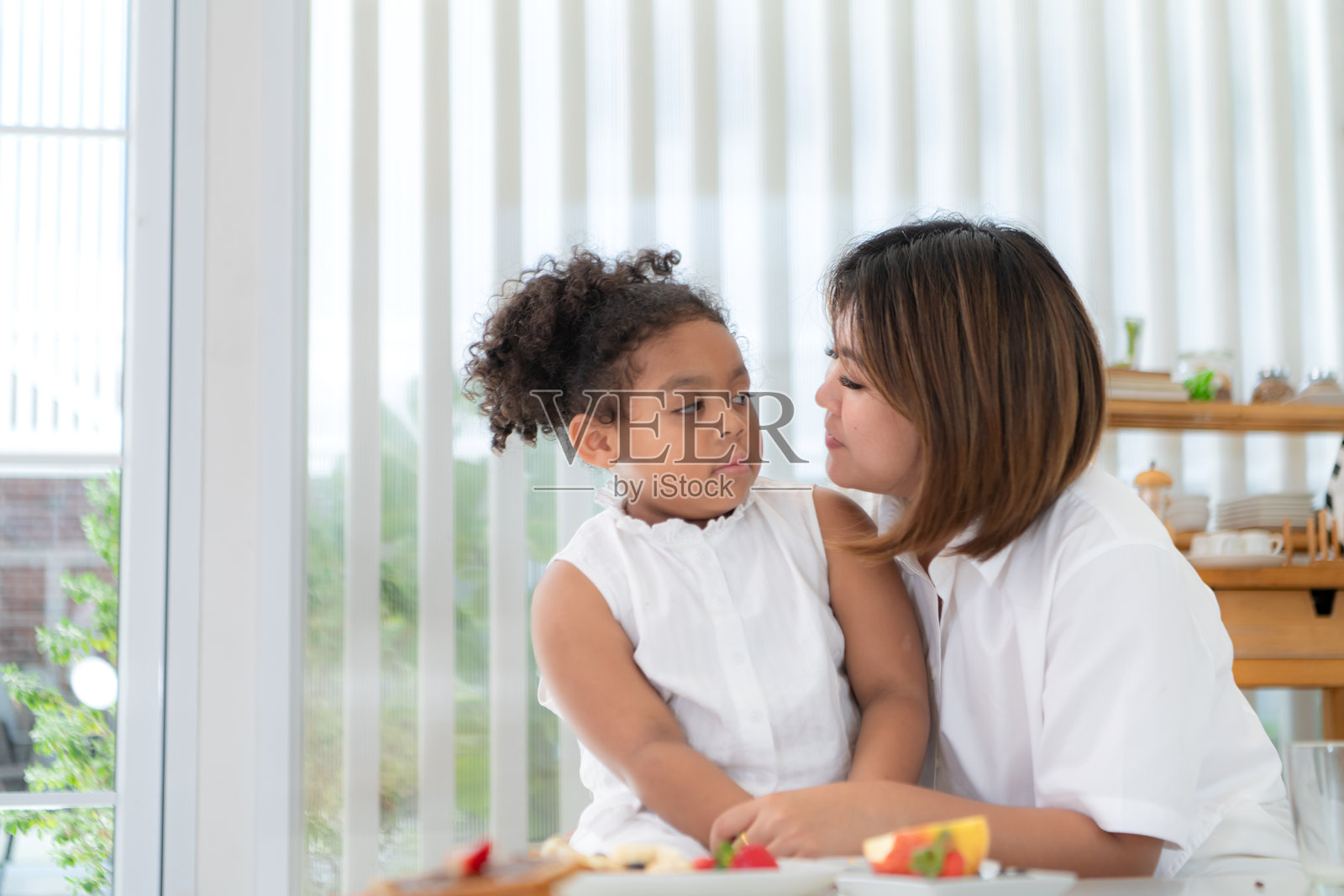 一个假日，一位妇女和她的小女孩坐在一所房子的客厅里吃水果照片摄影图片