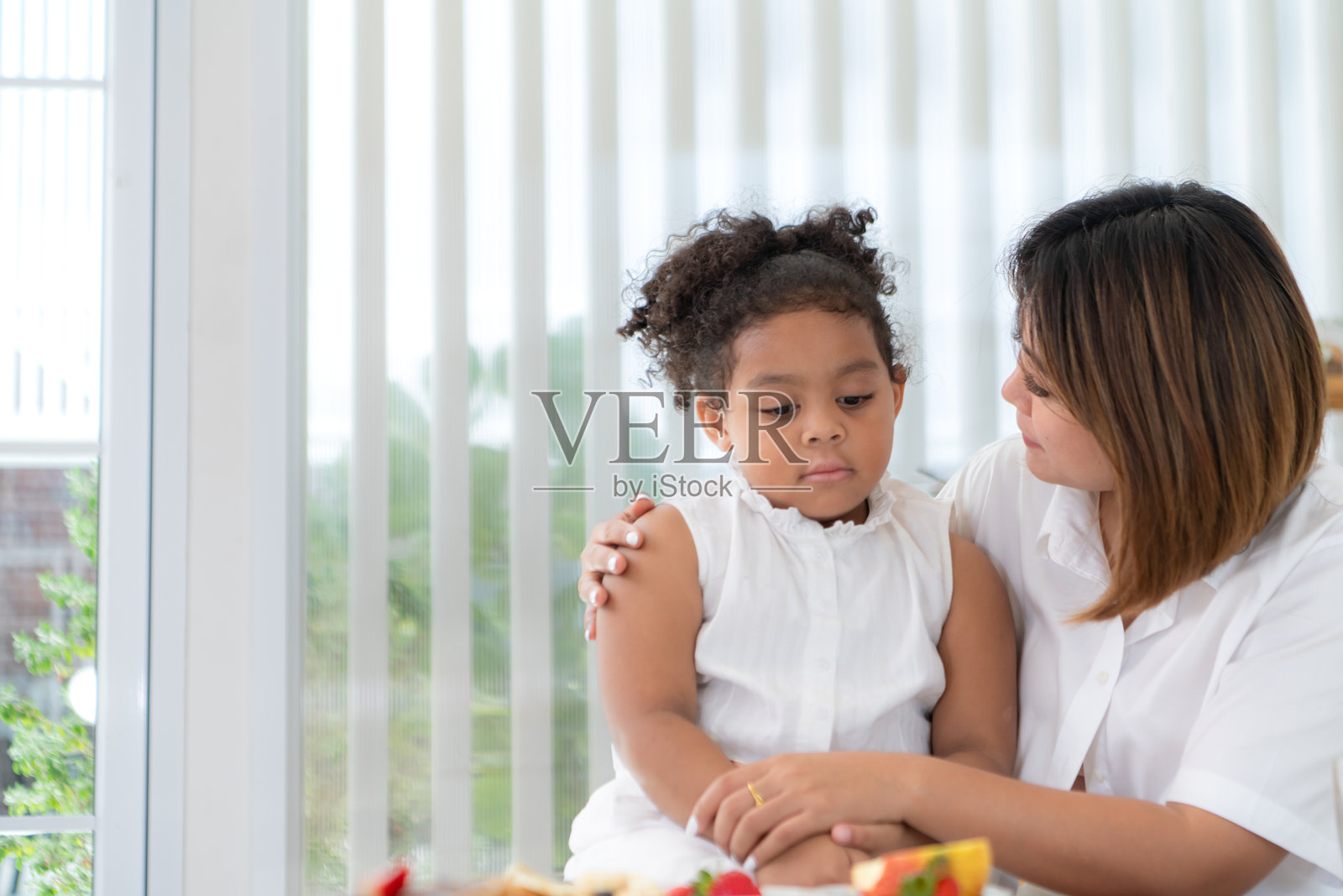 一个假日，一位妇女和她的小女孩坐在一所房子的客厅里吃水果照片摄影图片