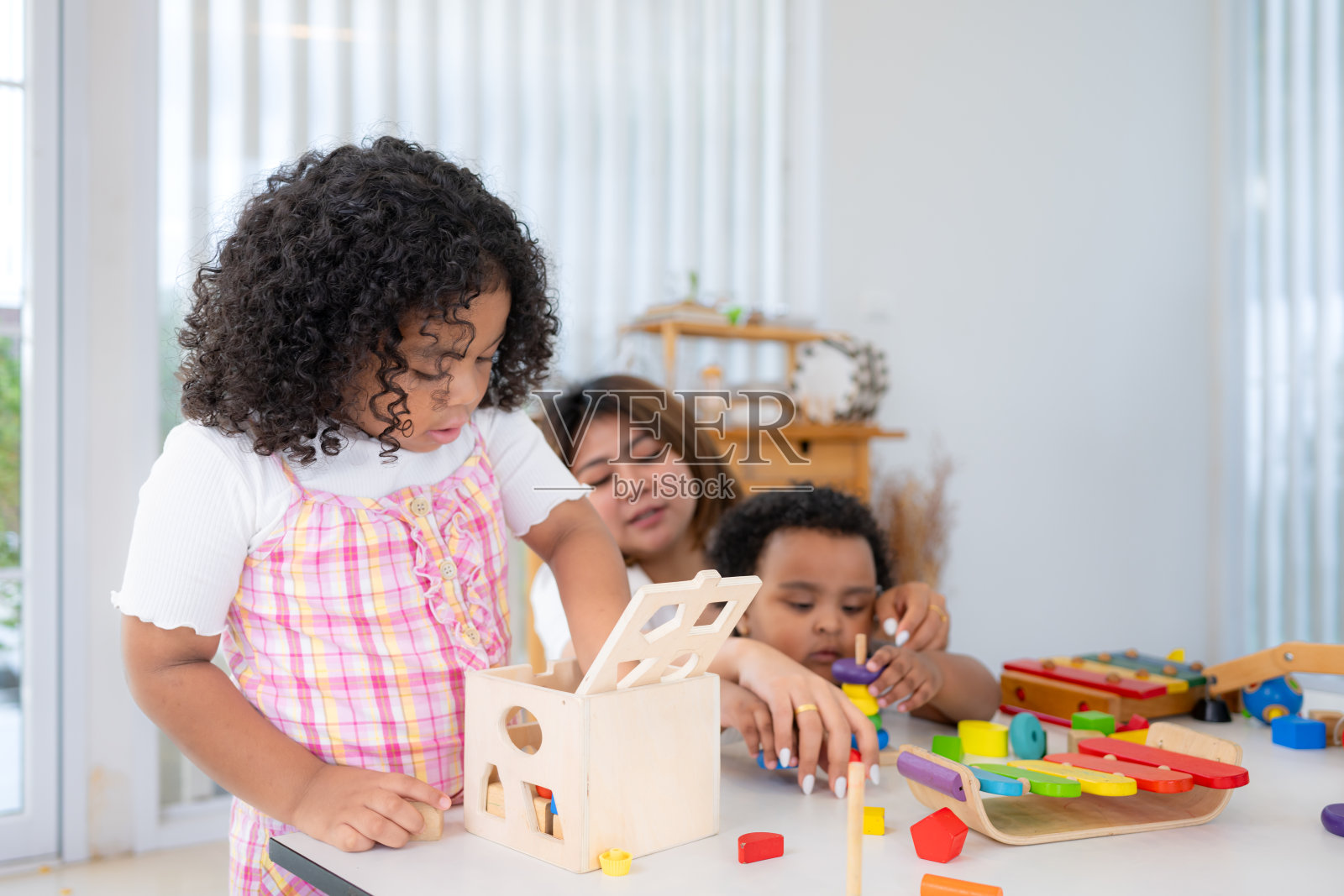 假日里，一位妇女和她的两个小女儿坐在地板上一起玩玩具照片摄影图片