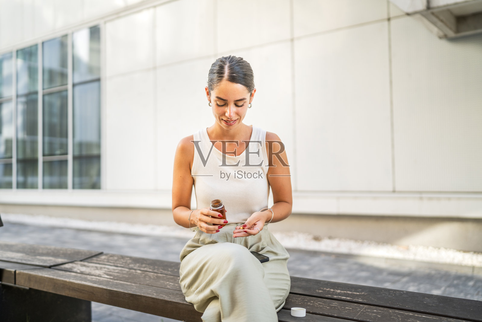 年轻女子在楼前服药，接受治疗照片摄影图片