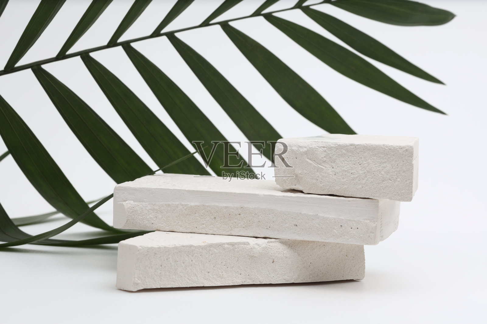 在灰色的光复制空间背景上堆叠石头、平台、讲台和棕榈叶。最小空显示产品演示场景。照片摄影图片