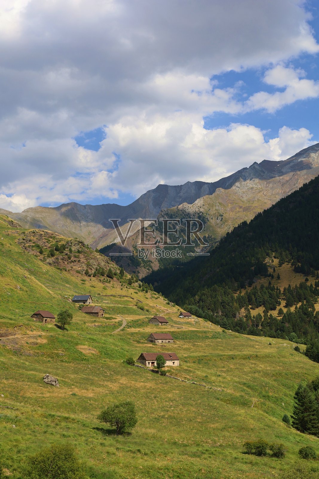 西班牙比利牛斯山脉历史悠久的维亚多斯村。绿色草地中古老的石头牧羊人小屋，波塞特山巨大的岩石墙填补了贝纳斯克旁边的图像上部照片摄影图片