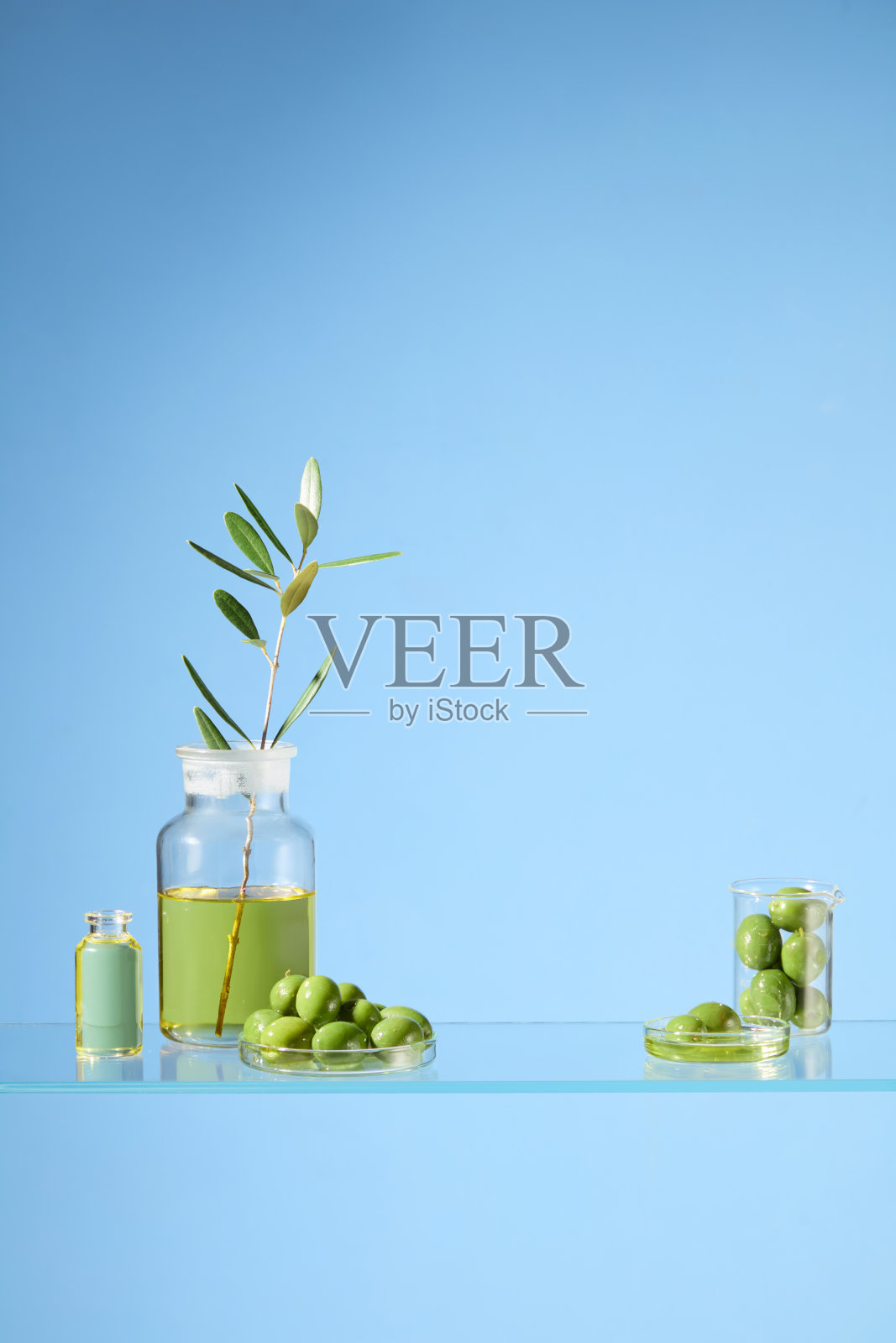 橄榄产品广告创意照片拍摄，有益健康和美容。这张照片是用实验室的布局拍摄的，玻璃表面上放置着装有新鲜橄榄的玻璃器皿照片摄影图片